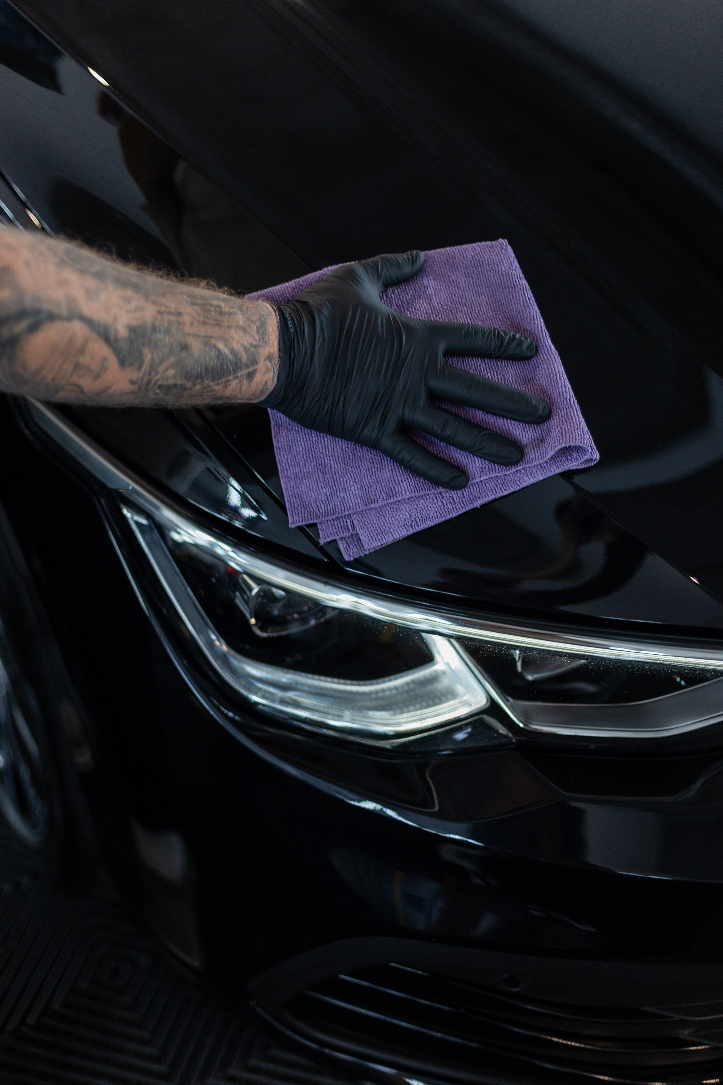 A man wipes a black car dry with a cloth. Detailing. Car care and washing