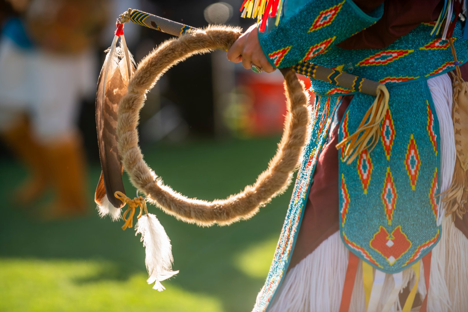 A Native American dancer performs at a Powwow in a colorful attire.