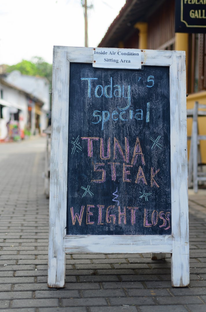 White wooden framed chalkboard, handwritten today's special menu, display on outdoor street pavement.