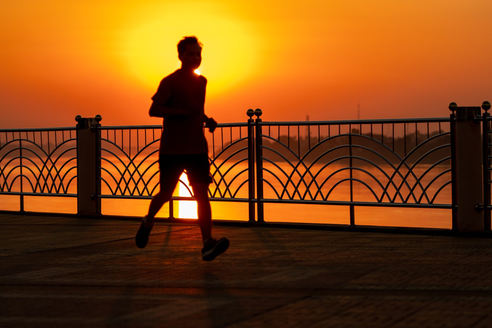 Male runners jogging during sunset Silhouette Behind the scenes are rivers and mountains.