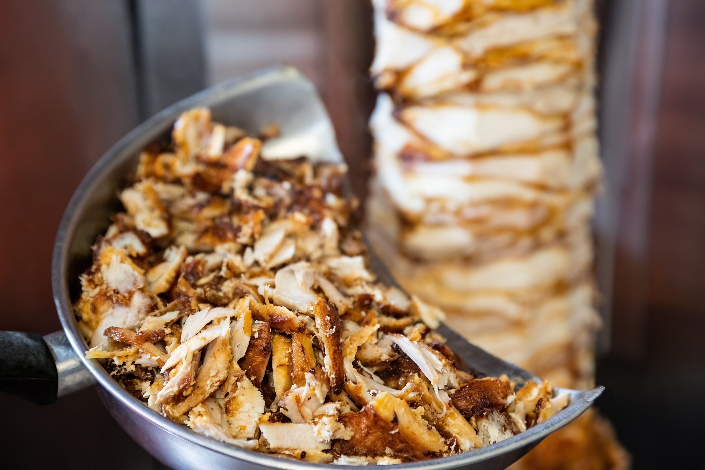 Juicy Greek traditional gyros grilled on fire and chopped for wrap sandwich, chicken meat doner, shawarma.