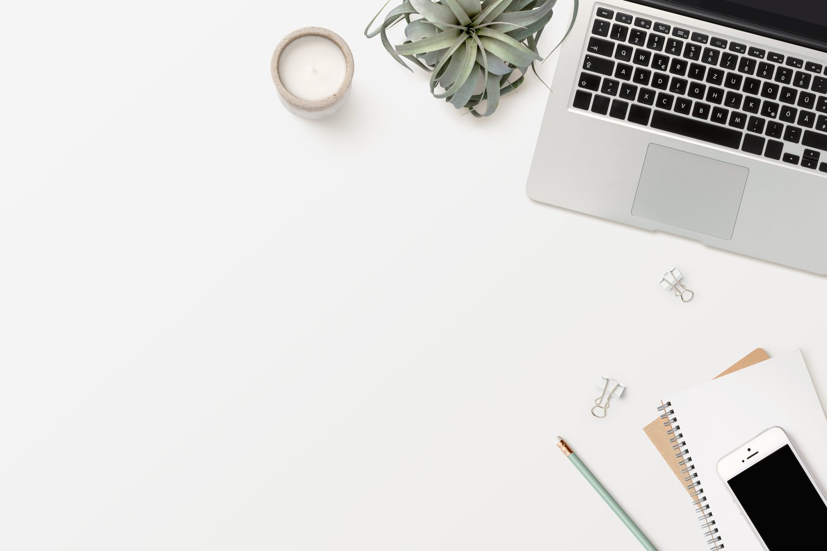 stylish modern minimalist workspace with laptop computer, white smartphone, office supplies, candle and an air plant (tillandsia) - flat lay / top view, copy space for text, a message or headline