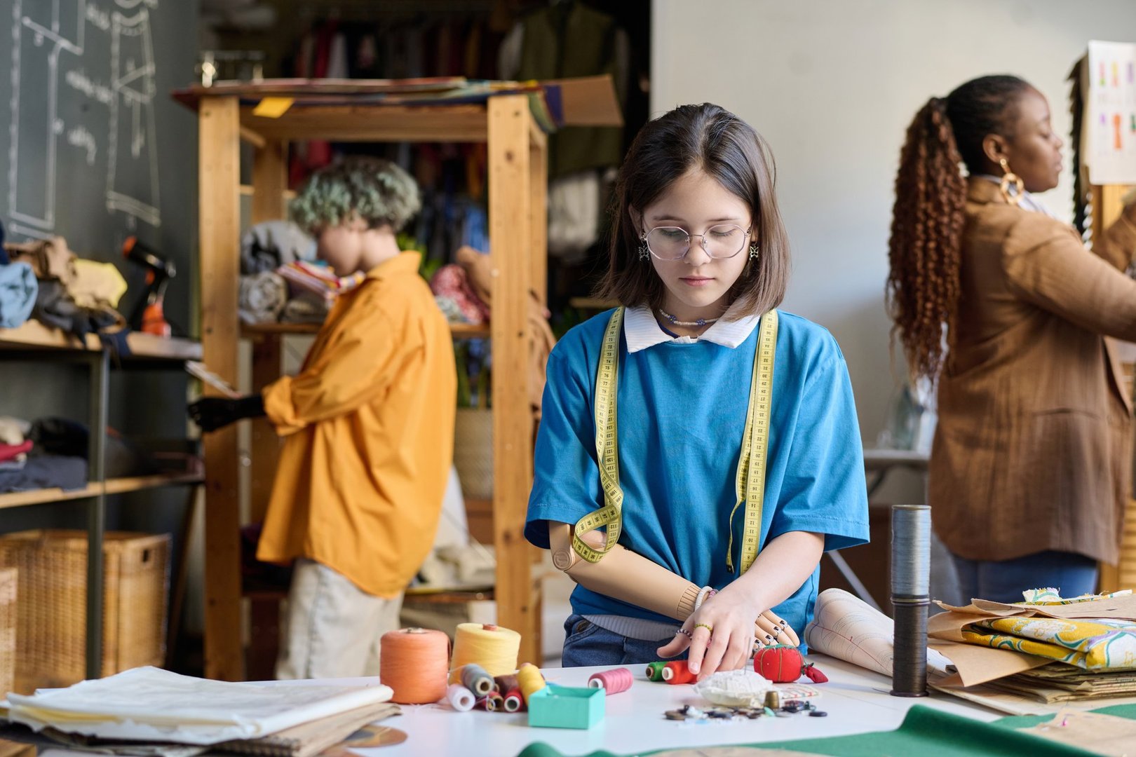 Waist up portrait of young girl with disability sorting threads by color in sewing class copy space