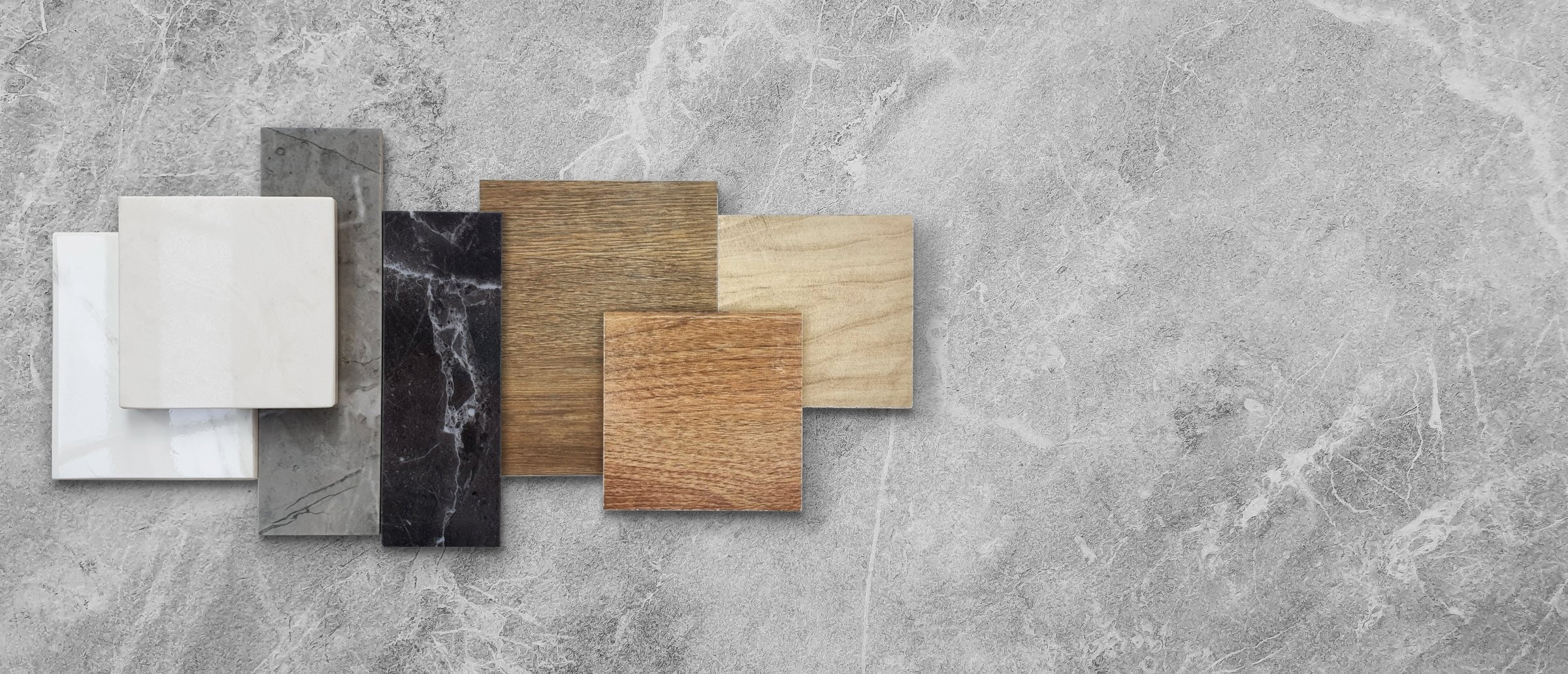 combination of interior material samples including wooden ceramic floor tiles, luxury marble stones, elegance artificial stone tiles placed on grey emperador marble table with blank space for design.