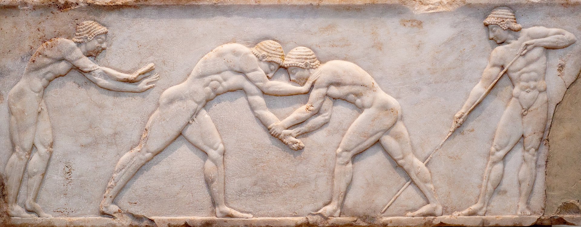 Ancient bas-relief on ancient Greek funerary stele from Kerameikos in Athens, Greece. Scene from Palaestra - wrestlers in action.