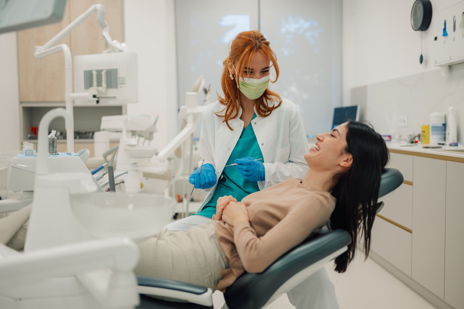 Female dentist wearing surgical mask talking with her patient in dental clinic