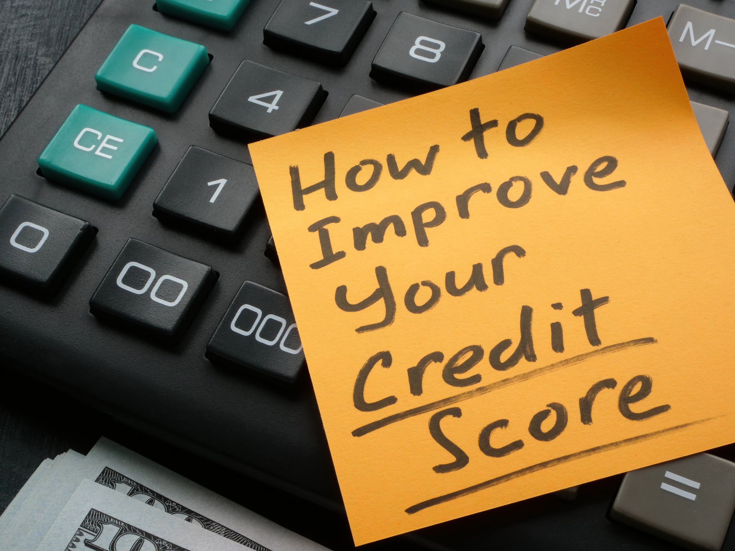 A Memo stick with How to improve your credit score inscription on the calculator.