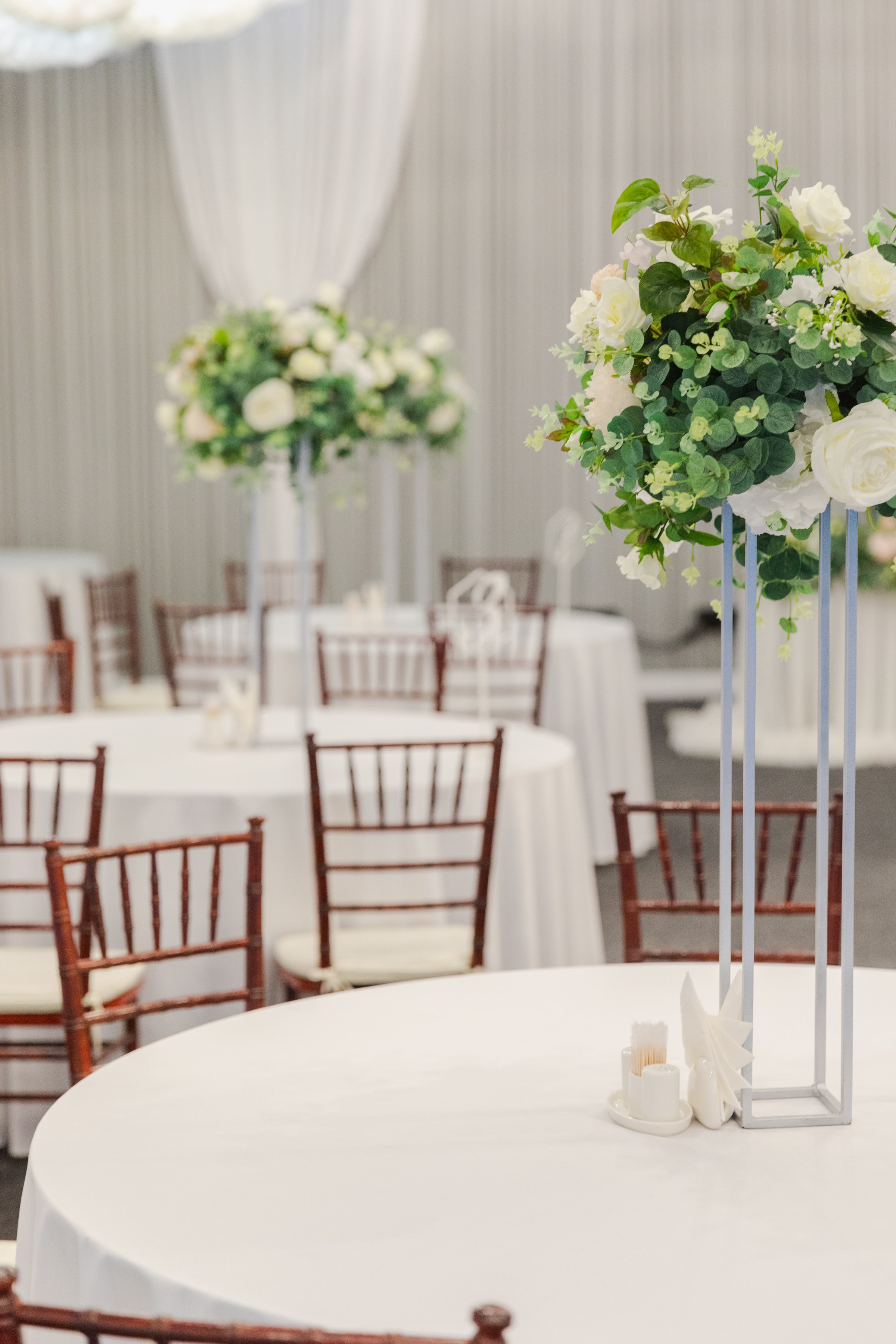 Decorated interior for festive event. Fancy table set for dinner with white flower composition in restaurant, luxury interior background. Wedding elegant banquet decoration arranged by catering service