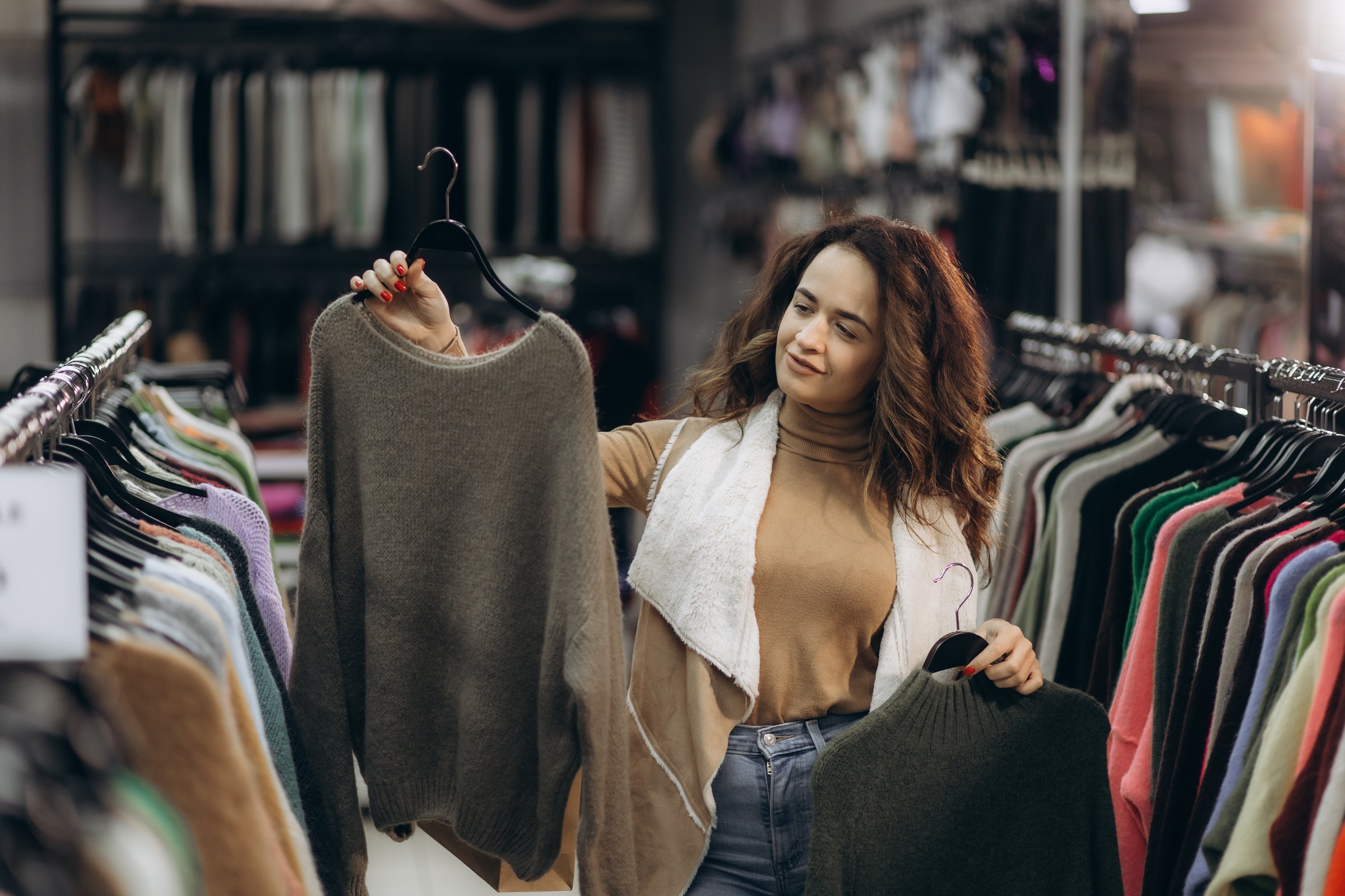 Woman examines sweaters in clothing store