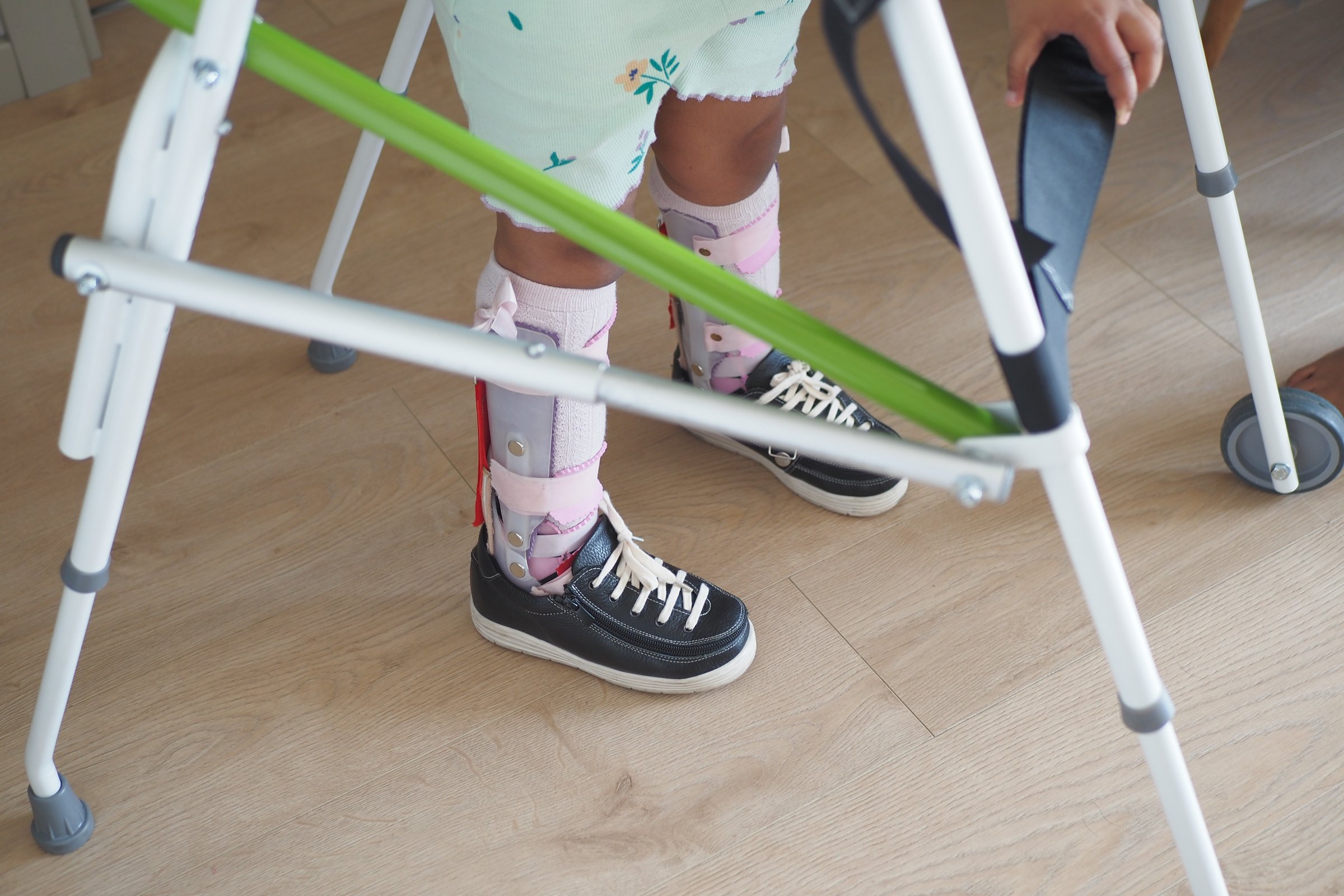 child with walking frame and knee orthosis outdoor .