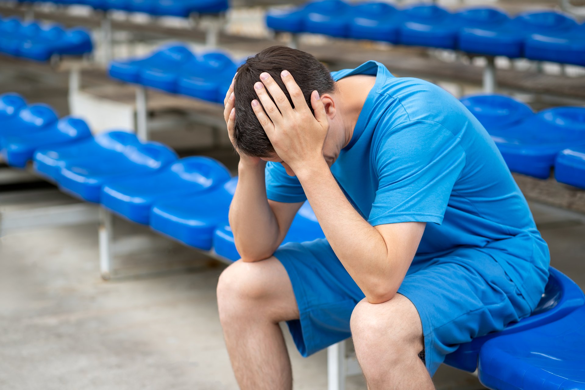 Headache and migraine, man with head pain after workout on a sports ground, health problems concept