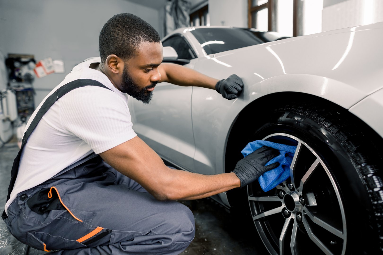 Professional mobile auto detailing technician working on luxury car at customer location, on-site car service