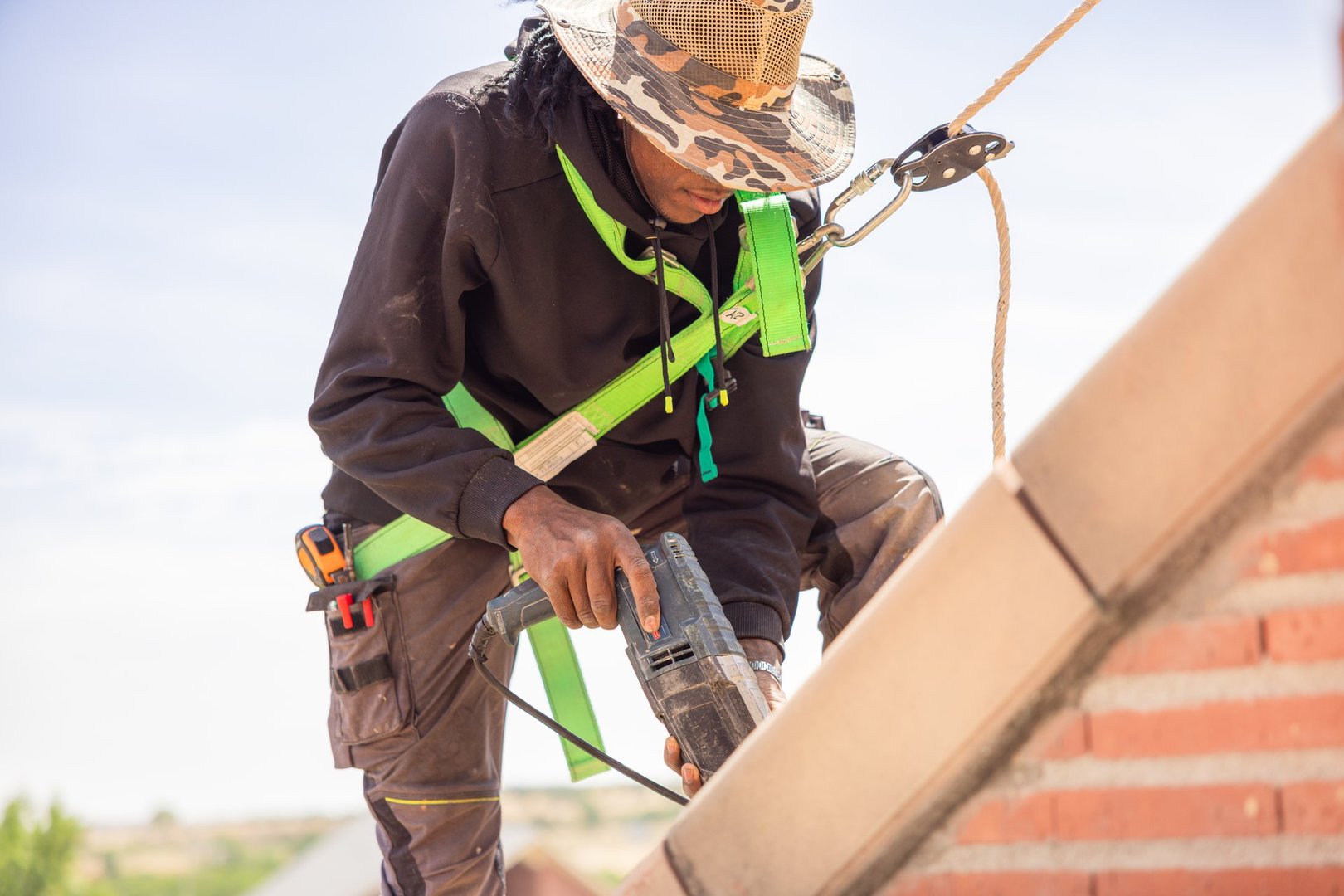 Professional roofer installing tiles with drill