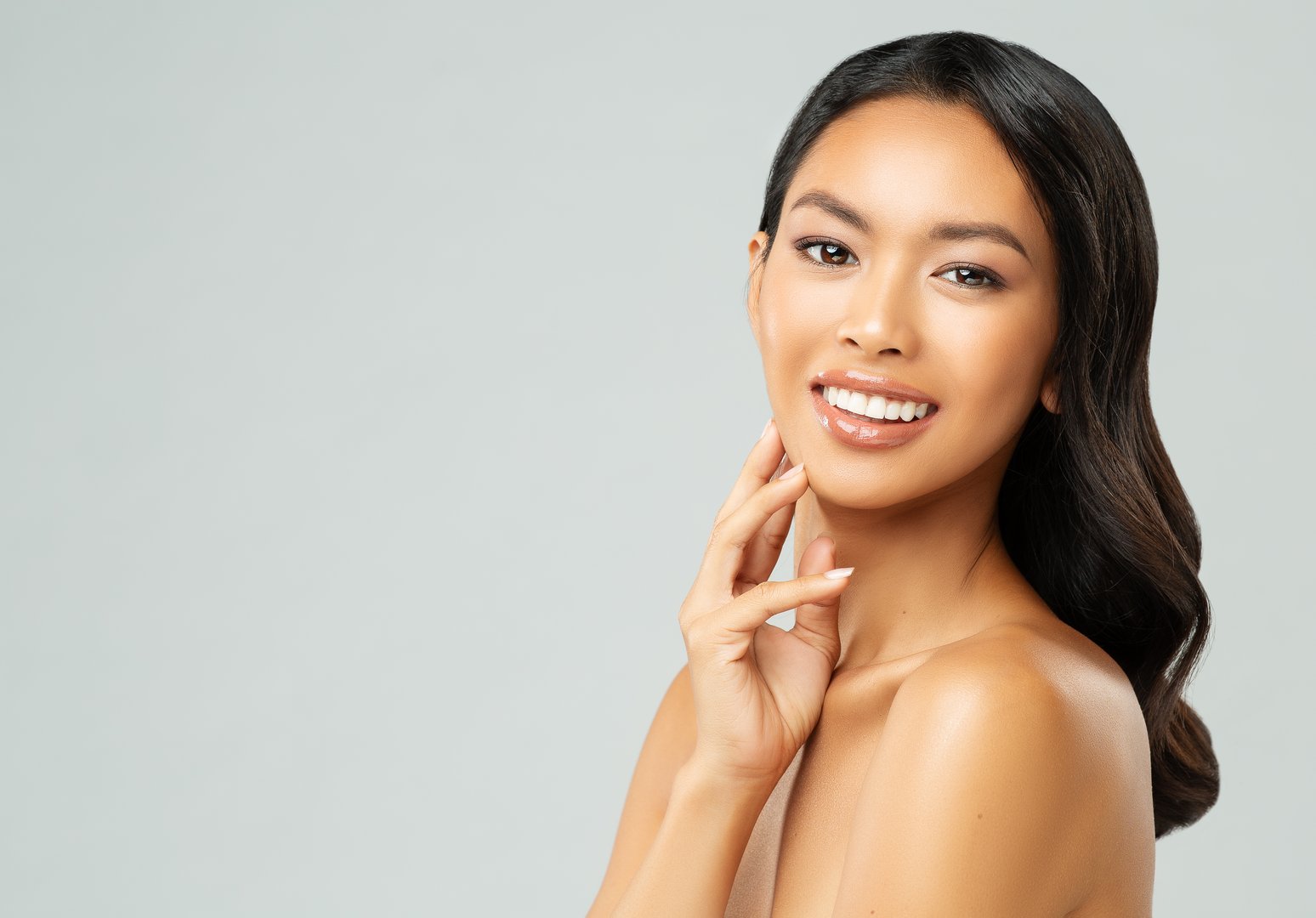 Beautiful Asian Woman happy smiling. Beauty Chinese Girl with Clean Skin over White studio background. Women Facial Spa Treatment and Face Care. Dermal Filler and Plastic Surgery