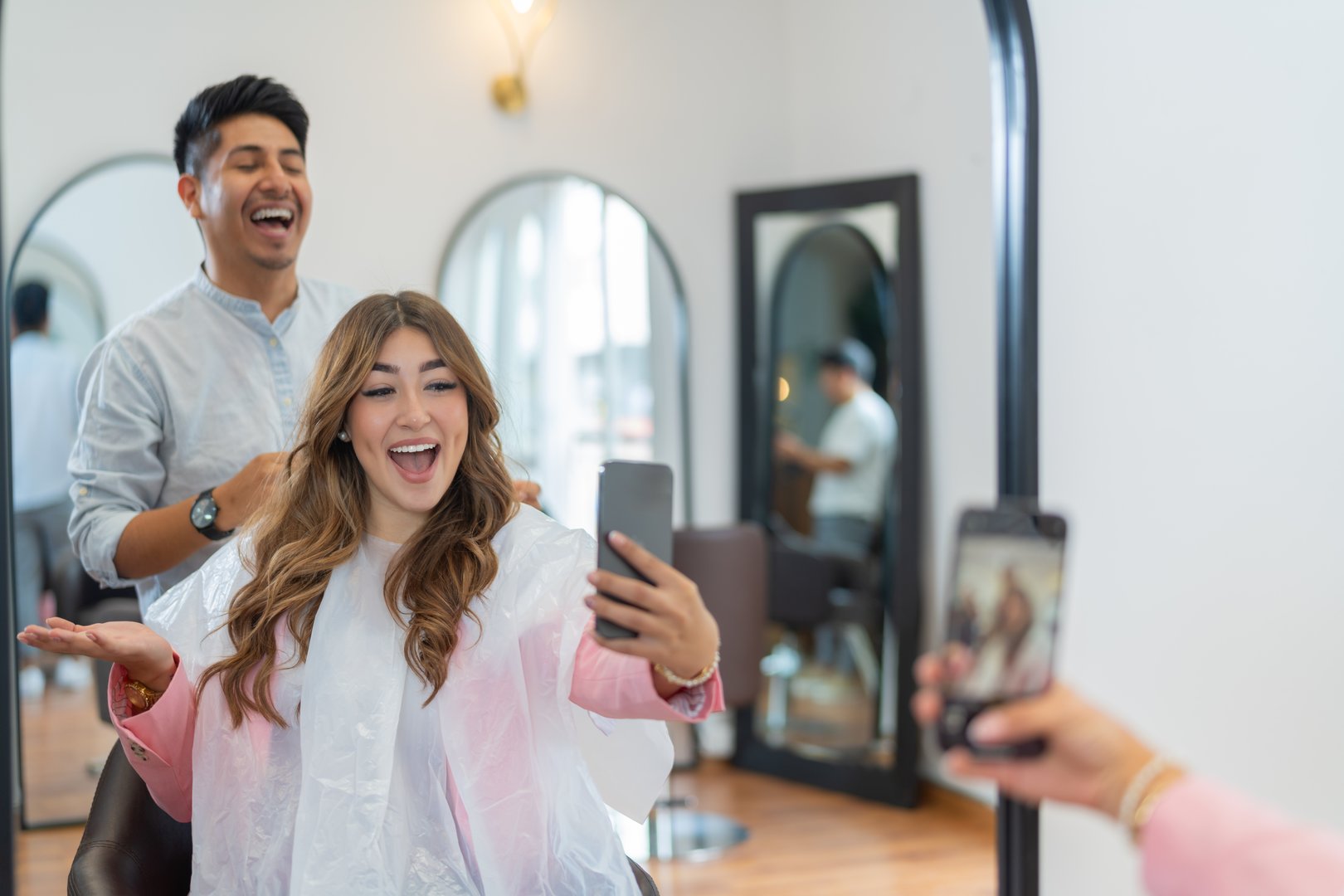 Happy and joyful influencer taking a selfie with a professional hairdresser in a salon