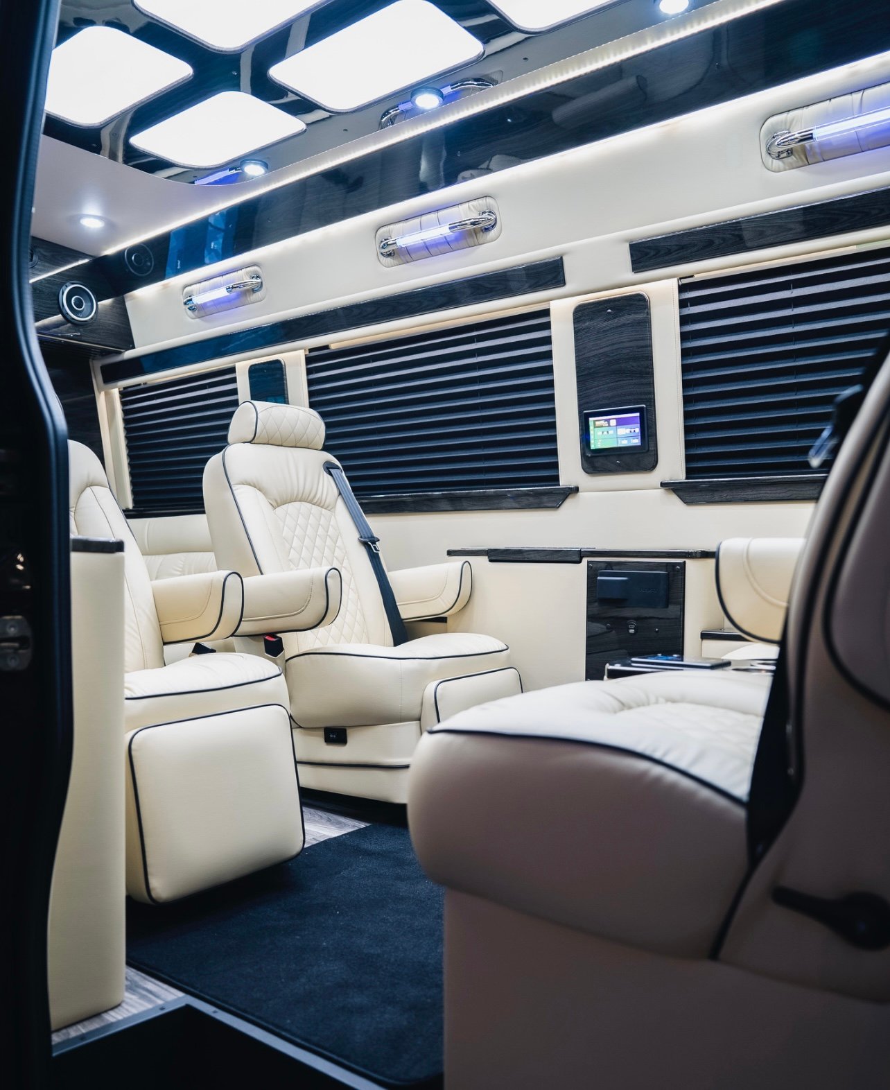Luxurious van interior with plush cream leather seats, ambient lighting, and wood accents.