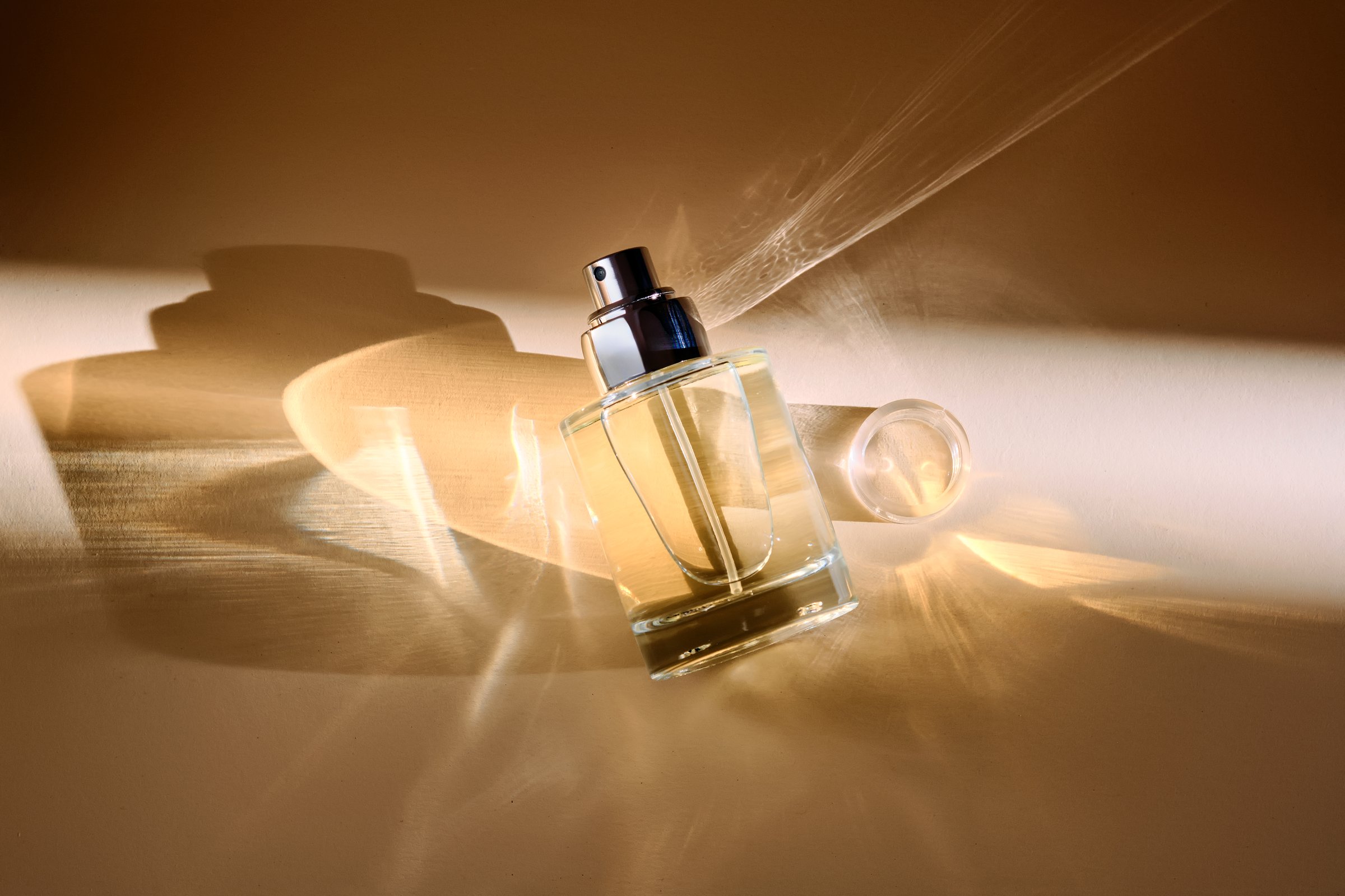 Perfume on a beige background in the rays of bright sun with beautiful highlights. High quality photo.