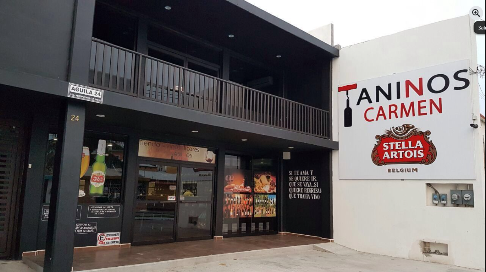 Front facade of Taninos Carmen bar featuring a large Stella Artois sign and glass doors with posters and decorations.
