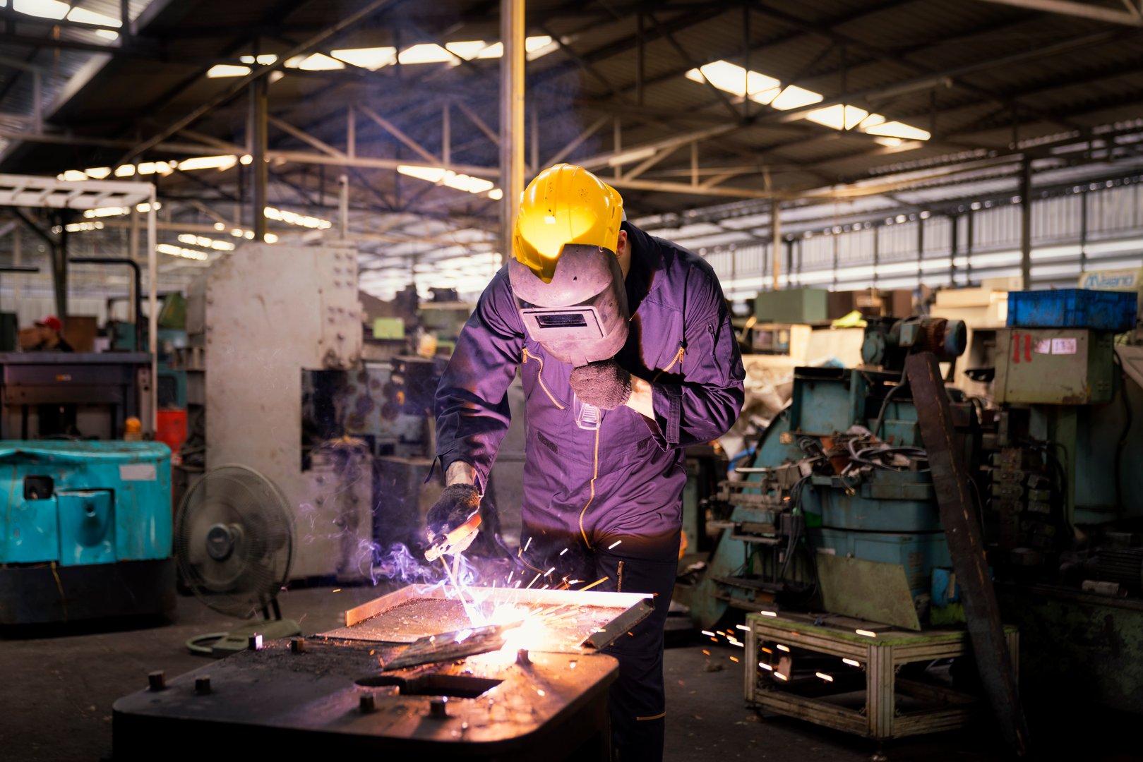 Factory technicians are welding young. Metal welding steel works using electric arc welding machine to weld steel at factory.