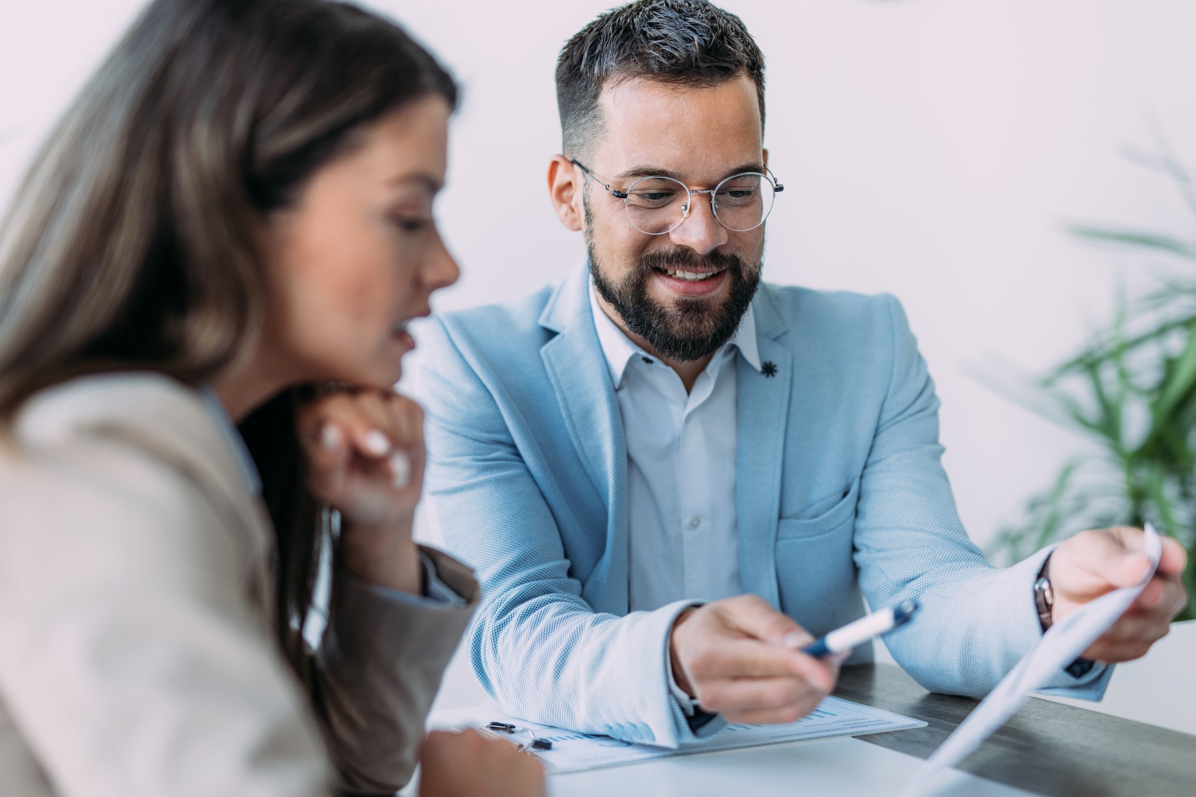 Shot of two young business persons on meeting in the office. Shot of businessman and businesswoman in meeting at the office. Business couple discussing important documentation in the workplace. Two business people in office working on business reports.