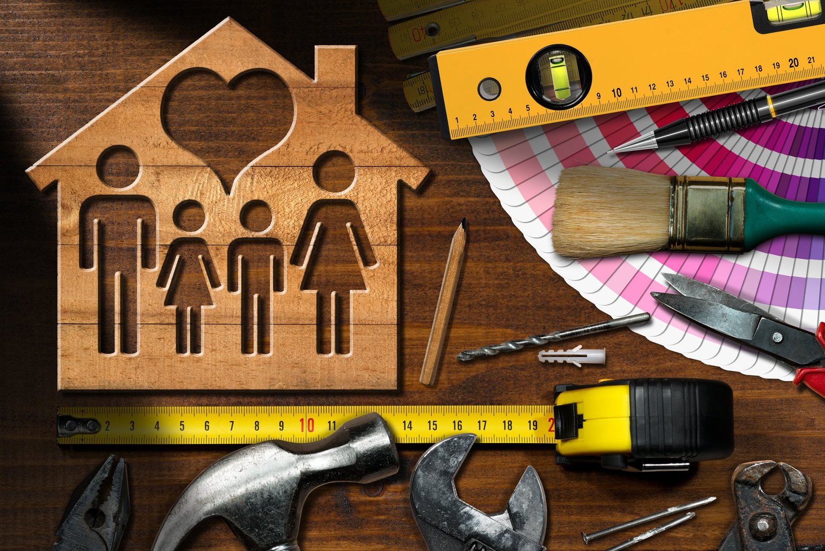 Home improvement concept - Wooden model house with a family and heart on a work table with tools