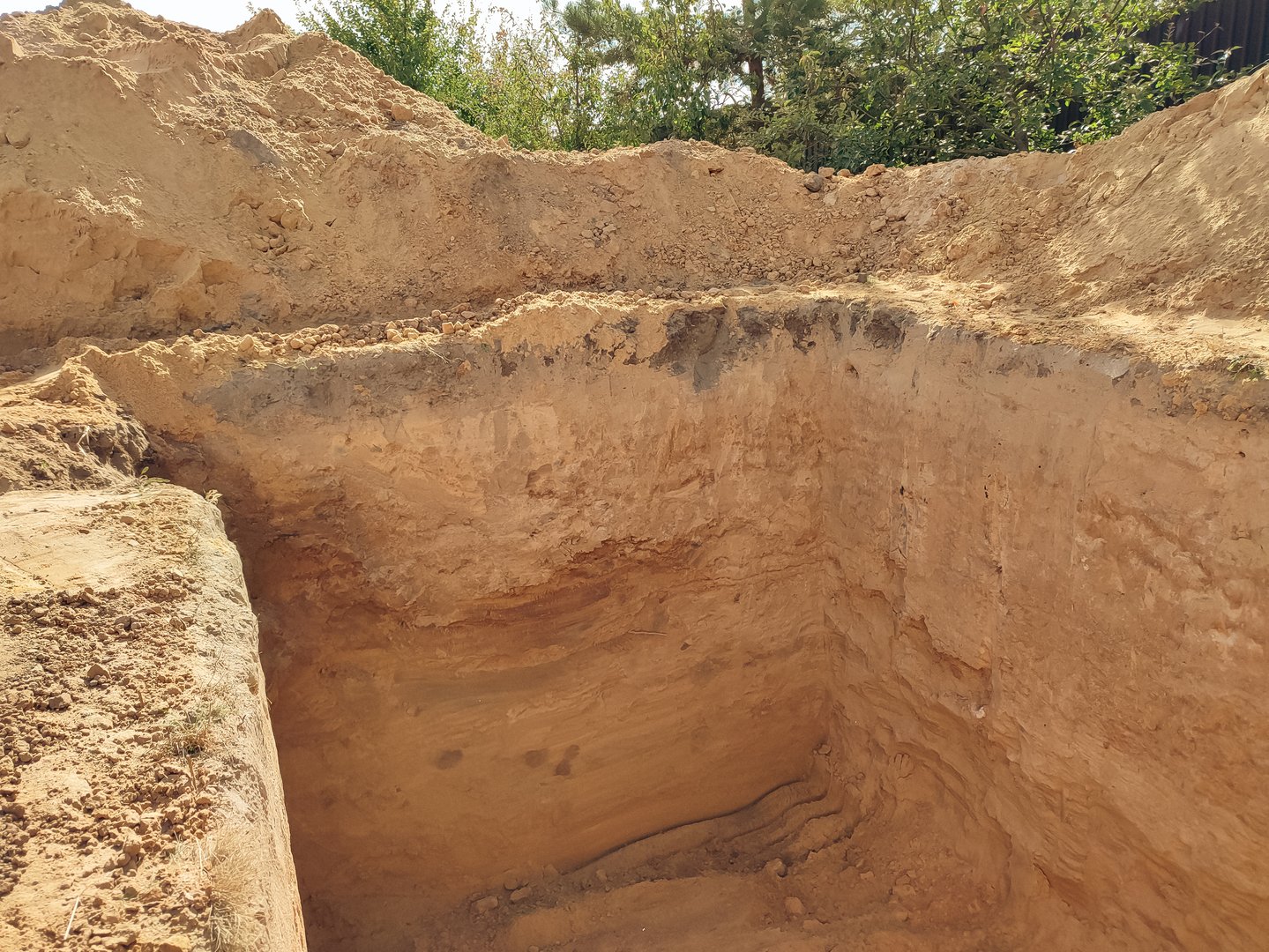 Large hole in the ground for a basement. Building works of new house concrete foundation on construction site. Digging a hole. Construction work in a private house
