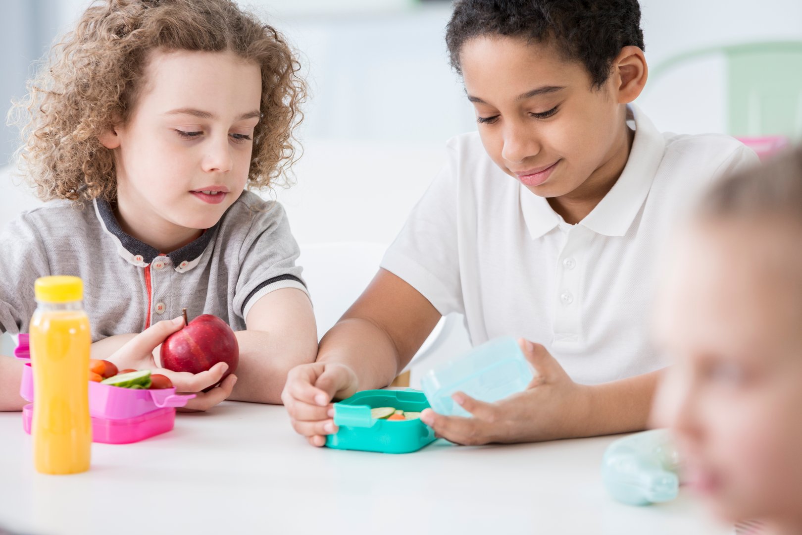 African-american boy and his friend eating apple and during break at school