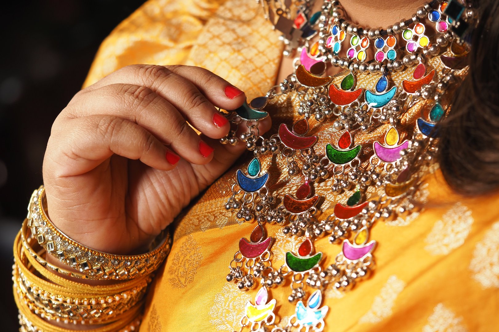 A person admires vibrant jewelry while dressed in traditional attire.