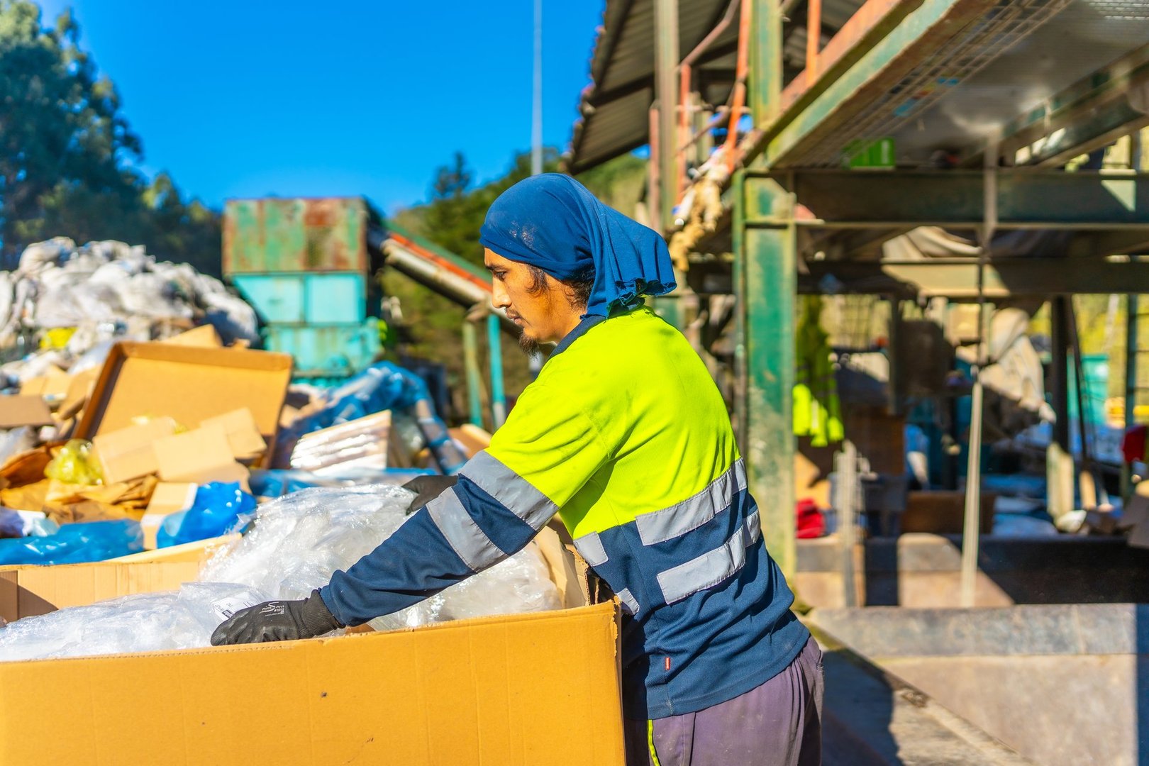 Side view photo of a latin male worker separating materials outside a recycling plant under the sun