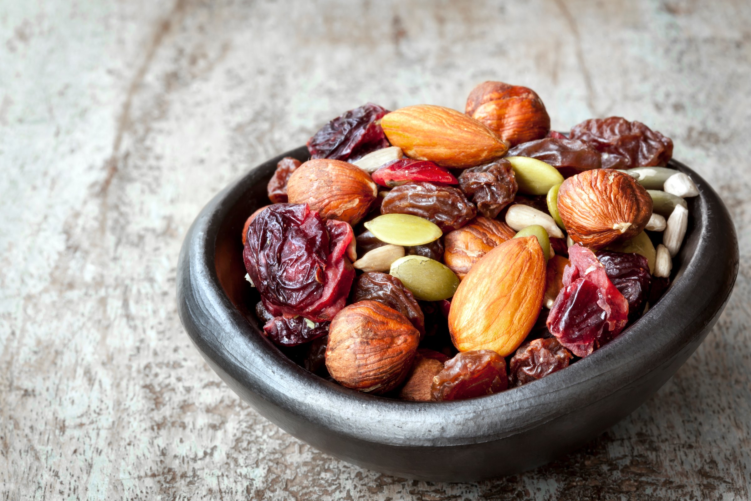 Trail mix in black bowl.  Delicious healthy fruit, nuts and seeds.
