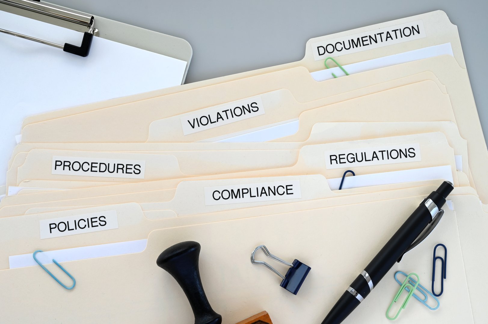 File folders marked Compliance Policies Regulations Violations Procedures and Documentation.