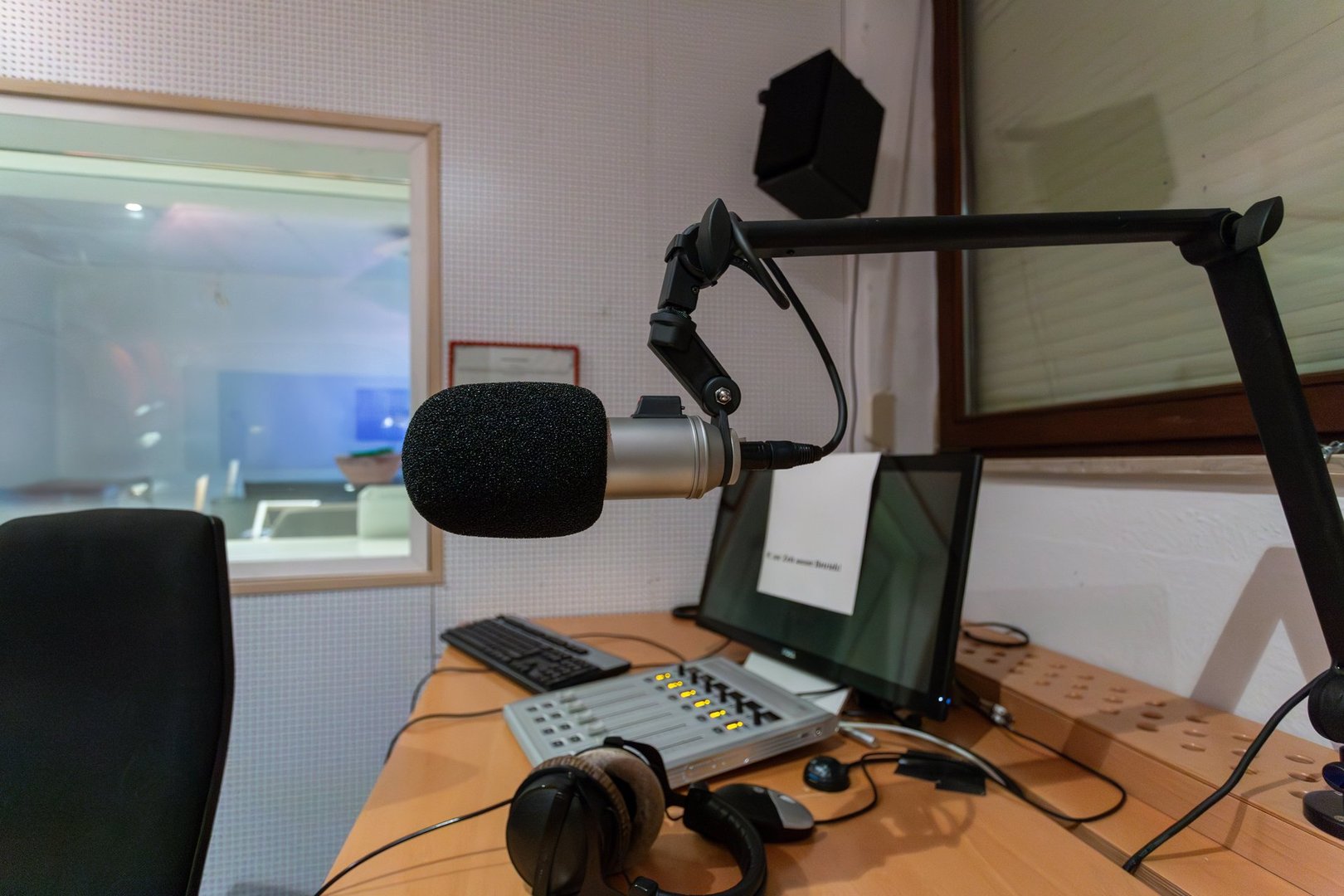 A radio studio is prepared for a live broadcast, showcasing a professional microphone, control panel, and sound equipment, with a focus on audio production.