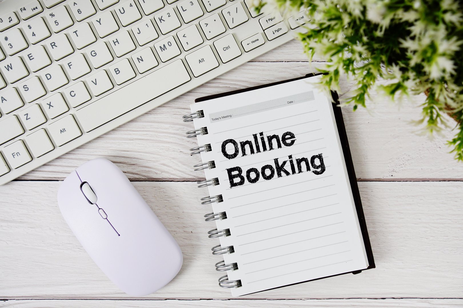 Online Booking text on notepad with keyboard and optical mouse on wooden background
