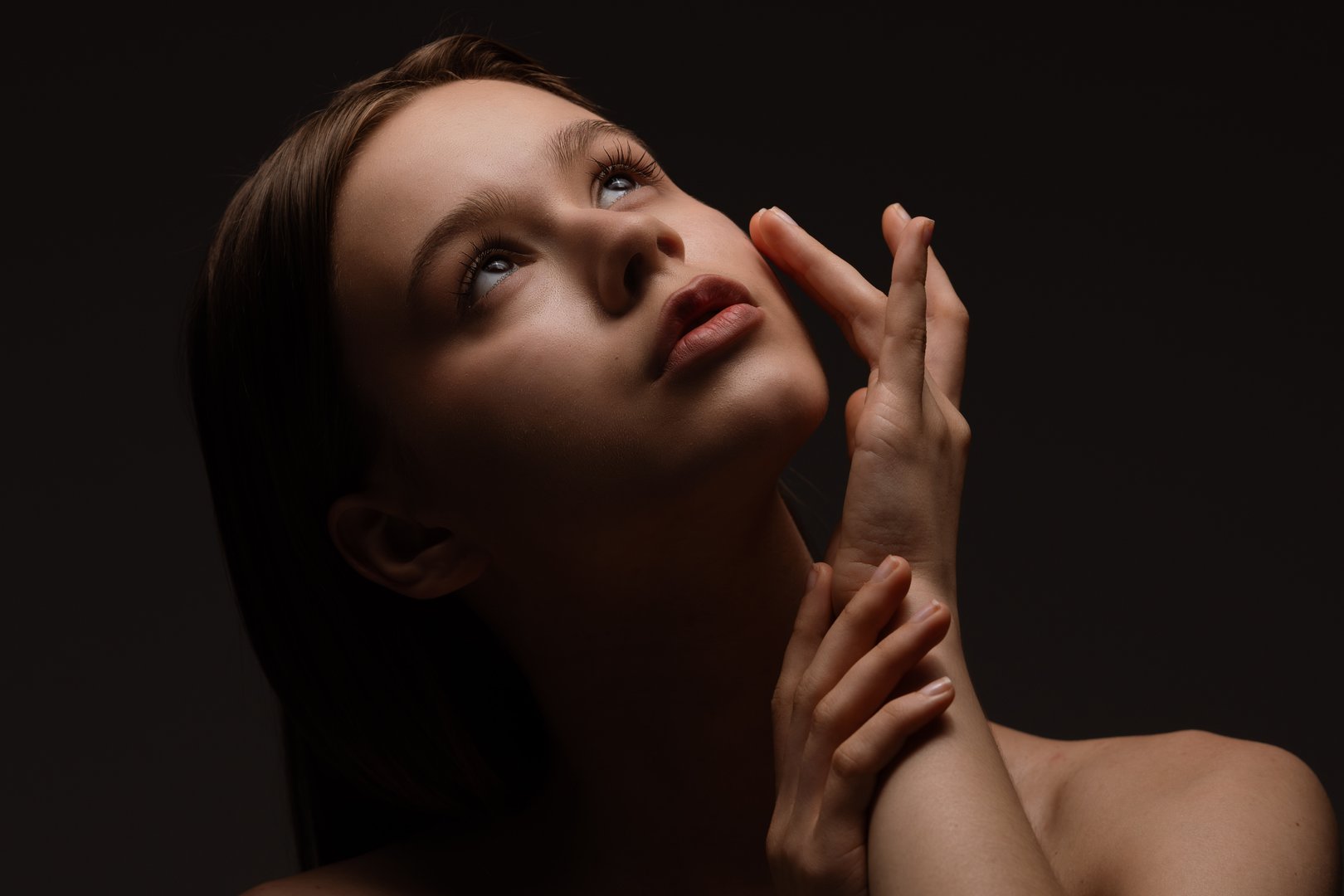 A captivating portrait of a young woman gazing upward with delicate expression, revealing elegance and depth.