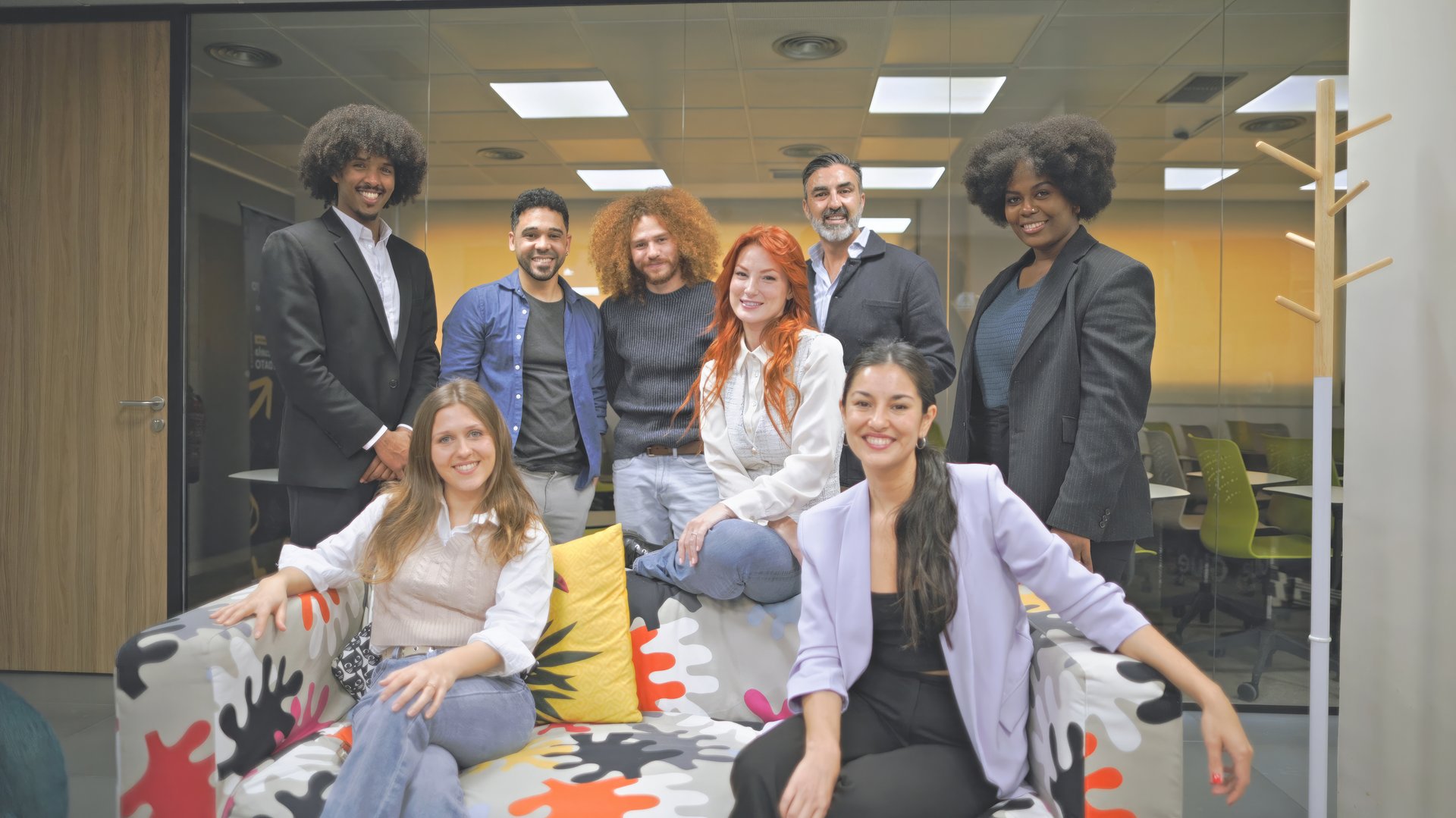 A diverse business team posing together in a modern office setting. The group includes men and women of different backgrounds, showcasing unity and professionalism.