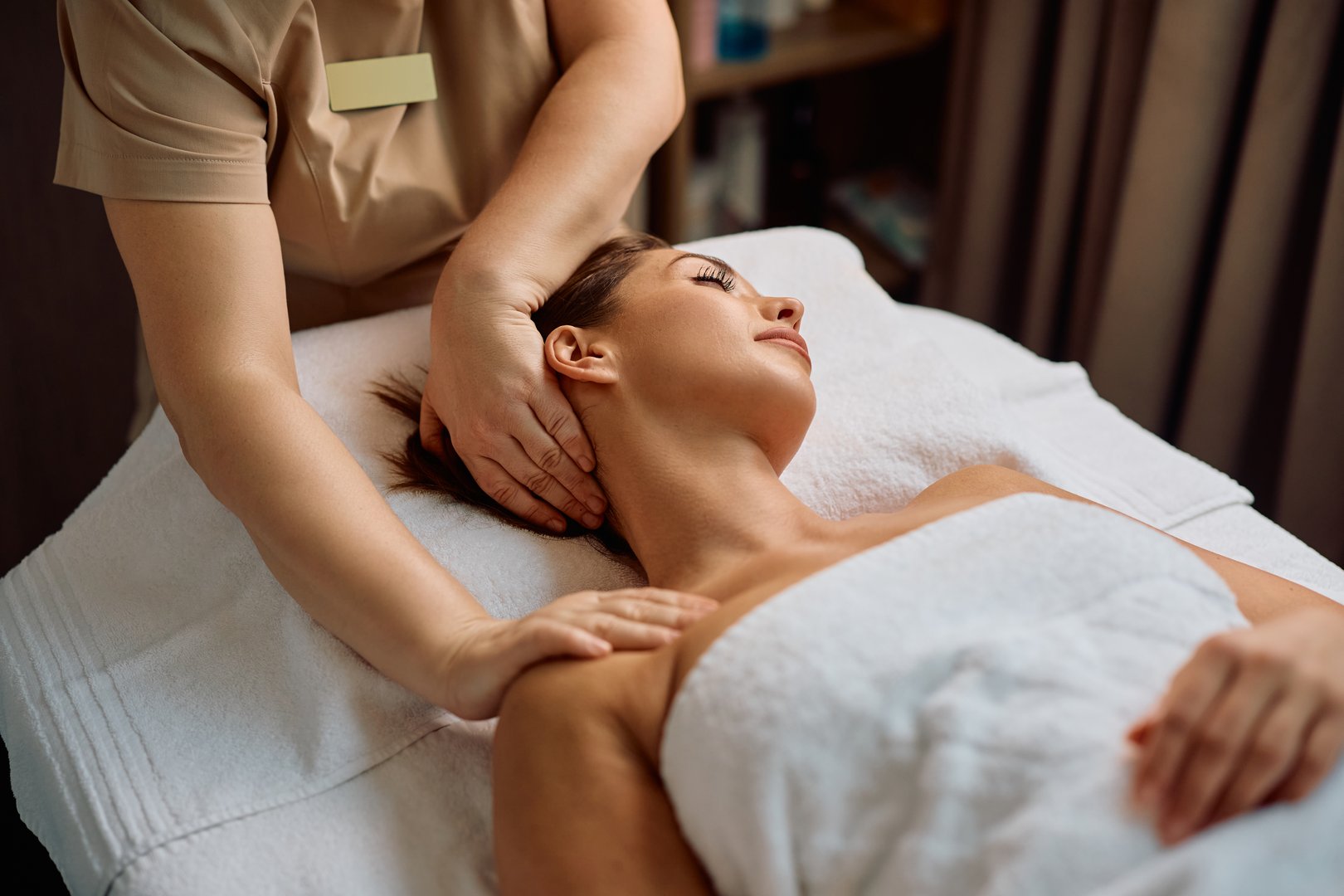 Young woman enjoying in spa treatment while receiving neck massage.