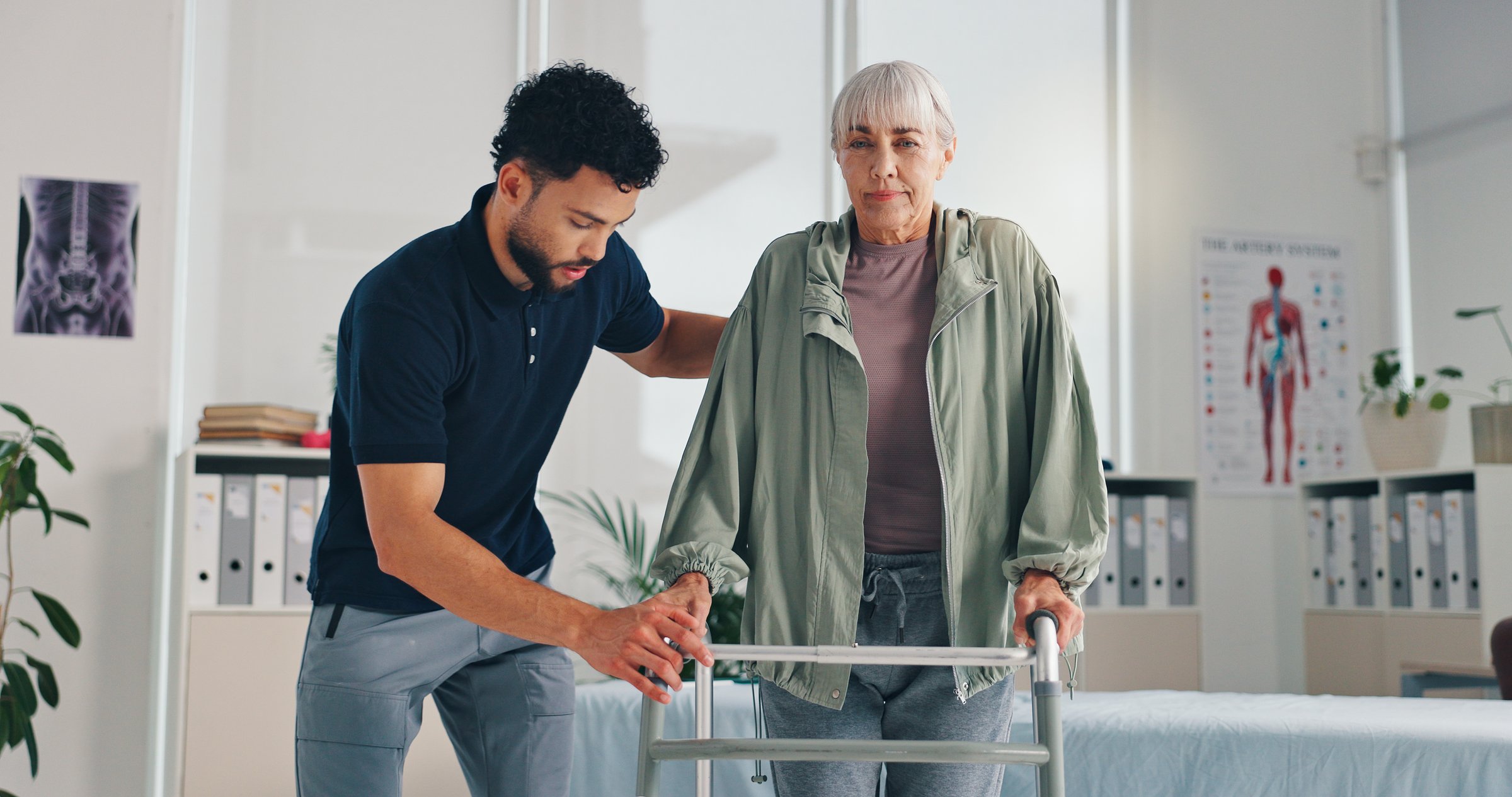 Senior woman, physical and help with walker for support, injury or arthritis at clinic. Patient, therapist and healthcare with walking frame, rehabilitation and recovery of muscle in osteoporosis