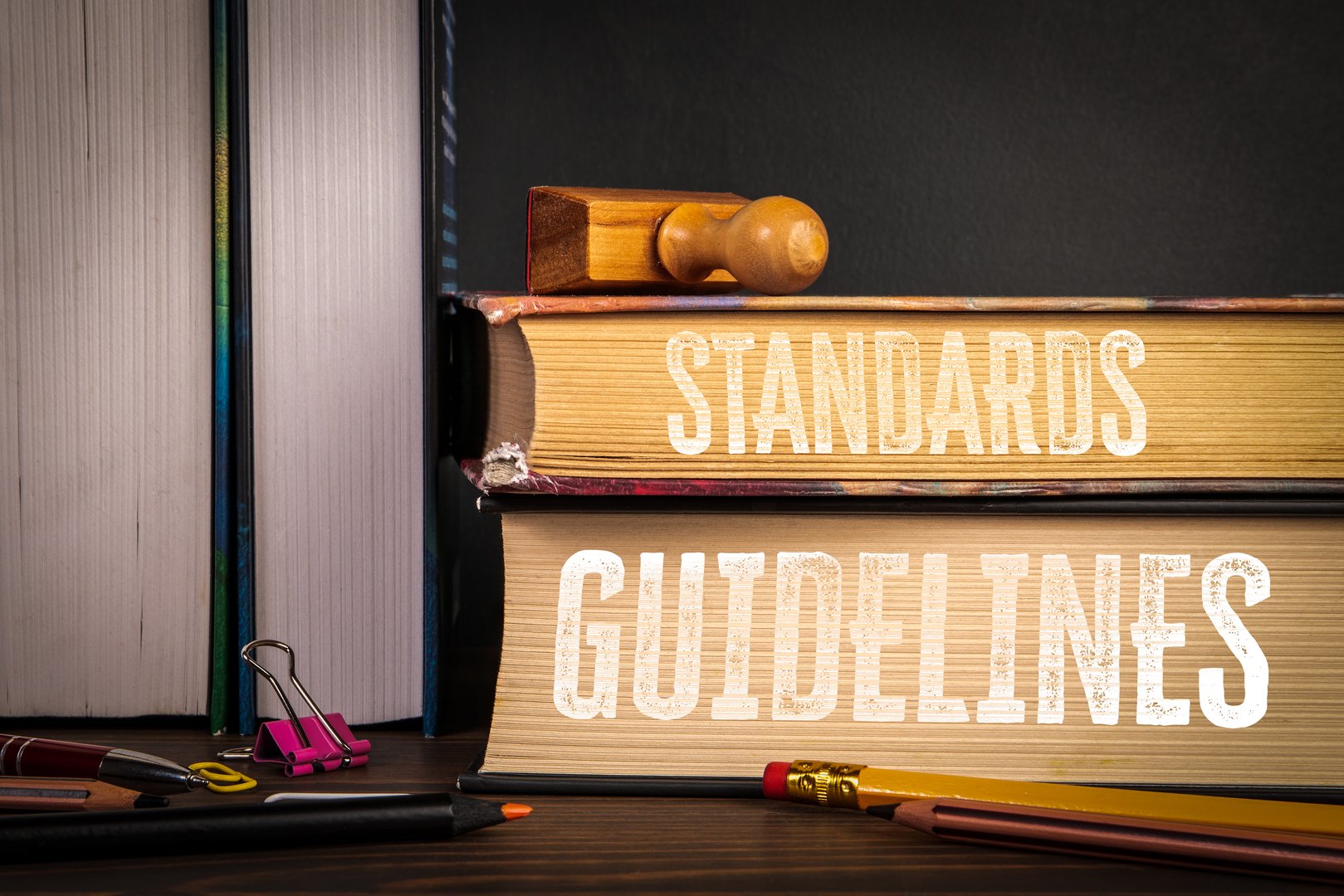 Standards and Guidelines. Books with Stamp and Office Supplies on Desk.