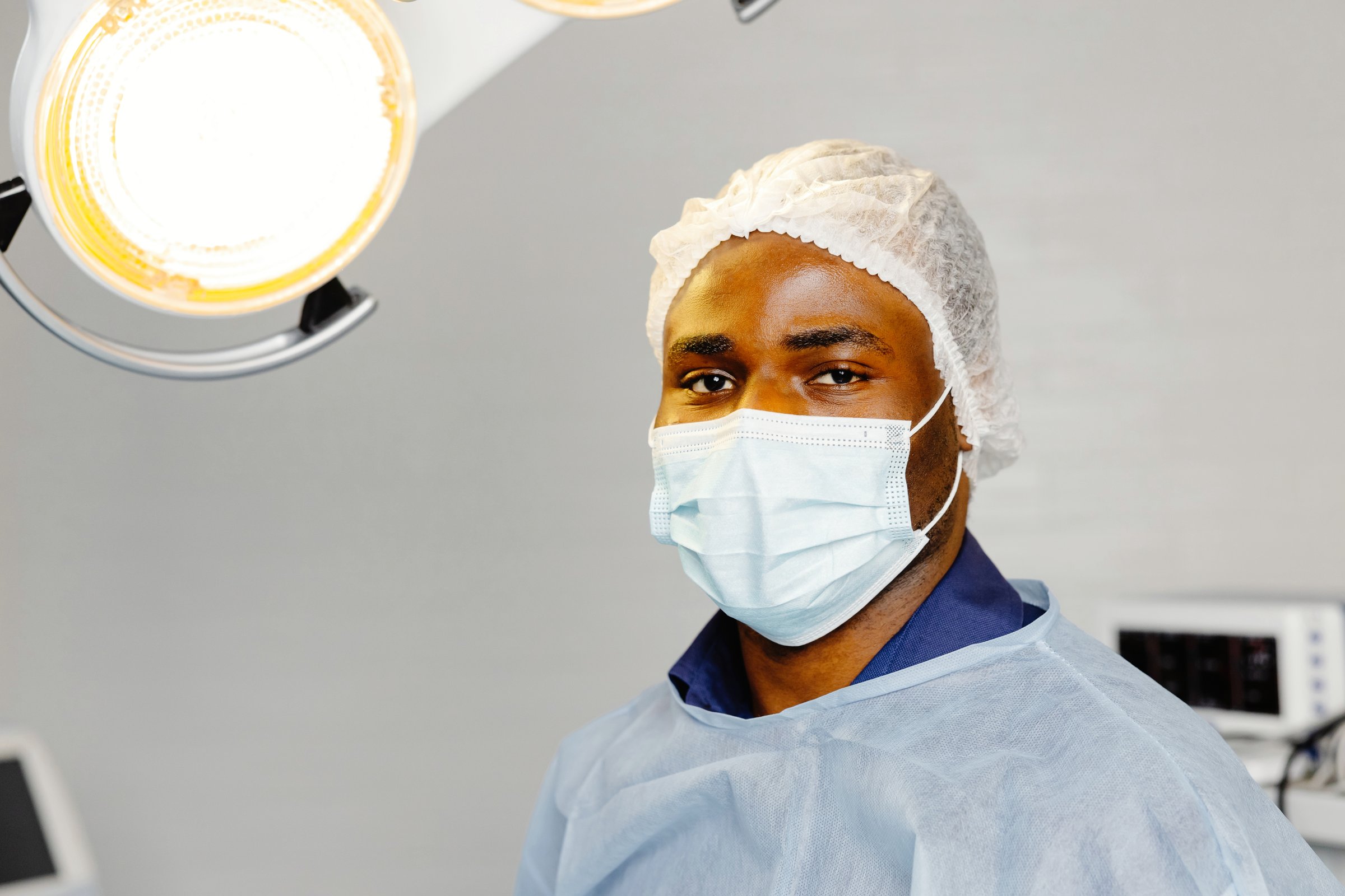 A man in a hospital setting wearing a surgical mask as a preventive measure against the spread of infectious diseases or viruses.