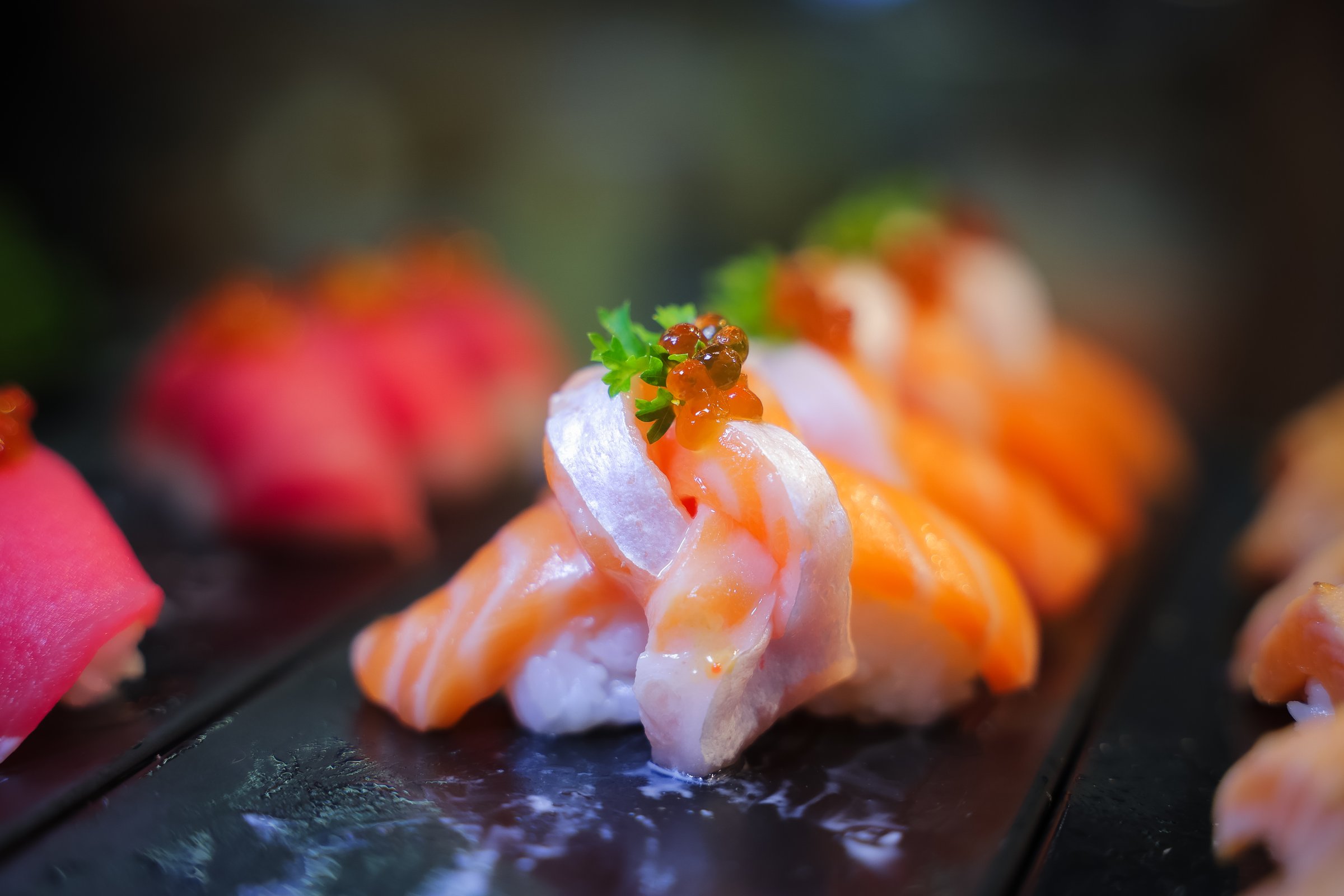 Salmon nigiri sushi in plastic box packaging tray on black stone slate background