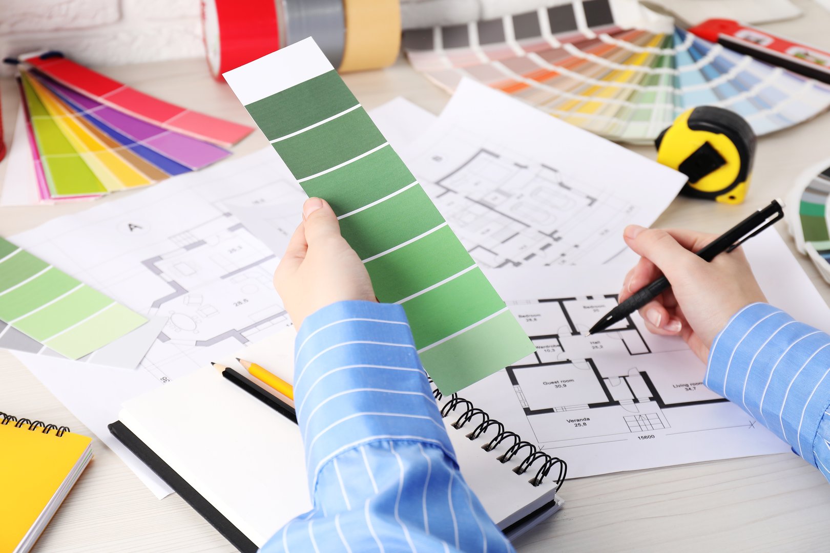 Designer with color selection chart working on house project at table, closeup
