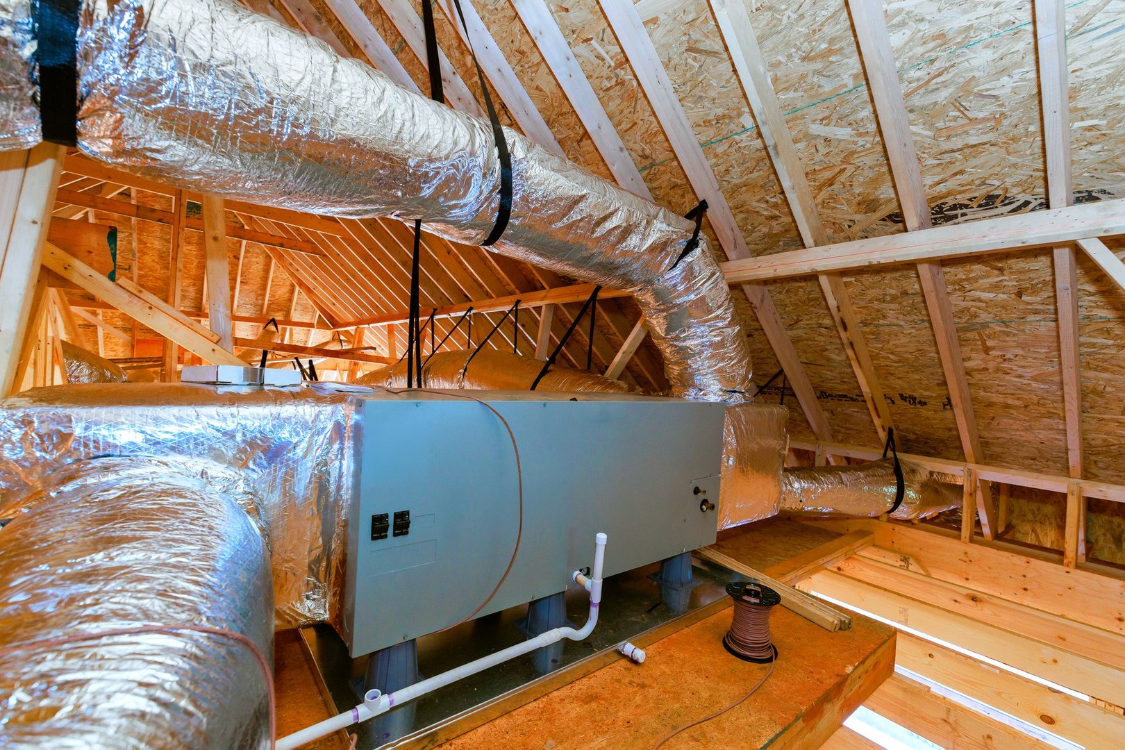 Workers install heating cooling system in attic of home during building phase