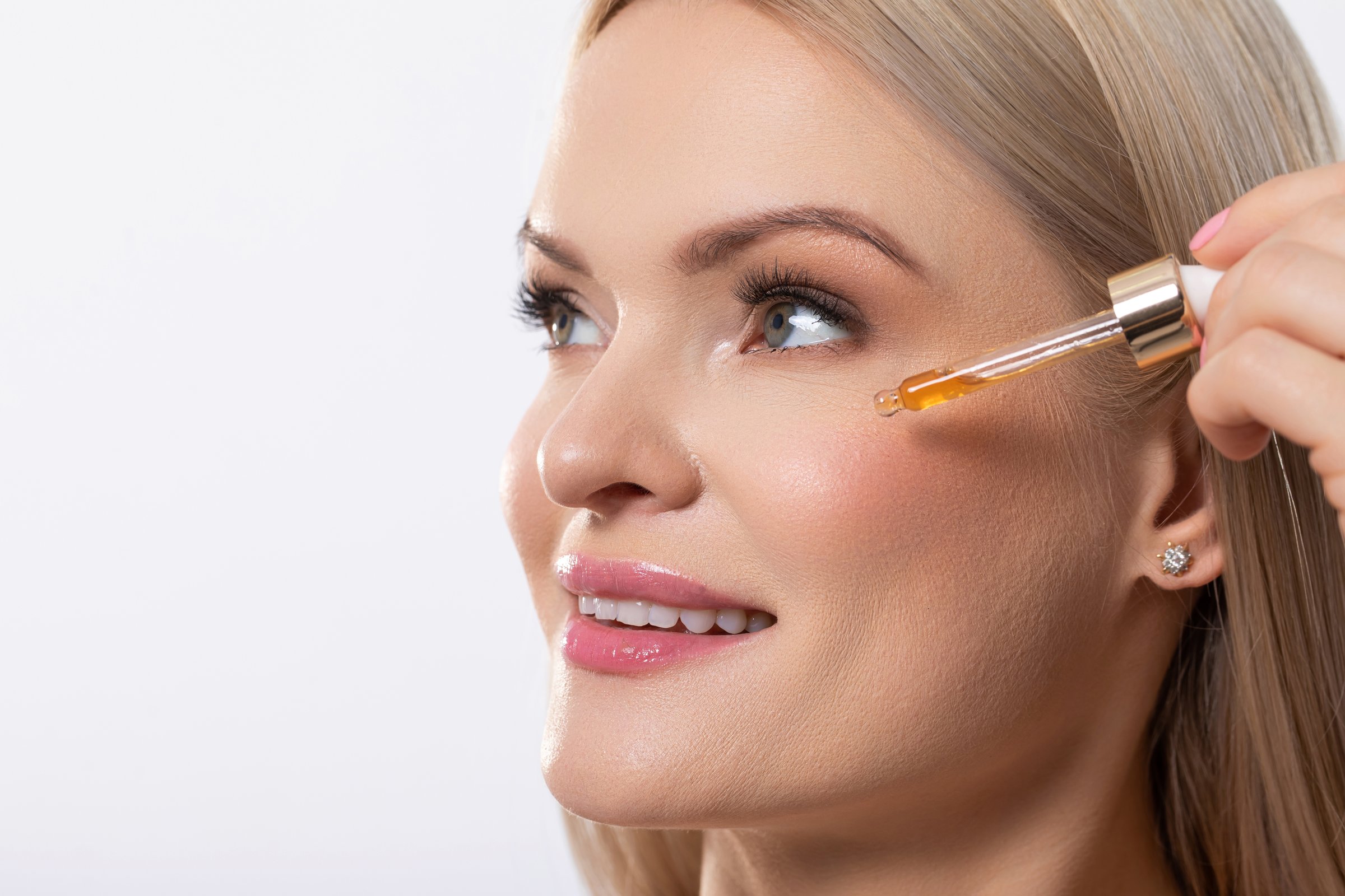 A woman is carefully applying a glowboosting serum to achieve a truly radiant and youthful appearance