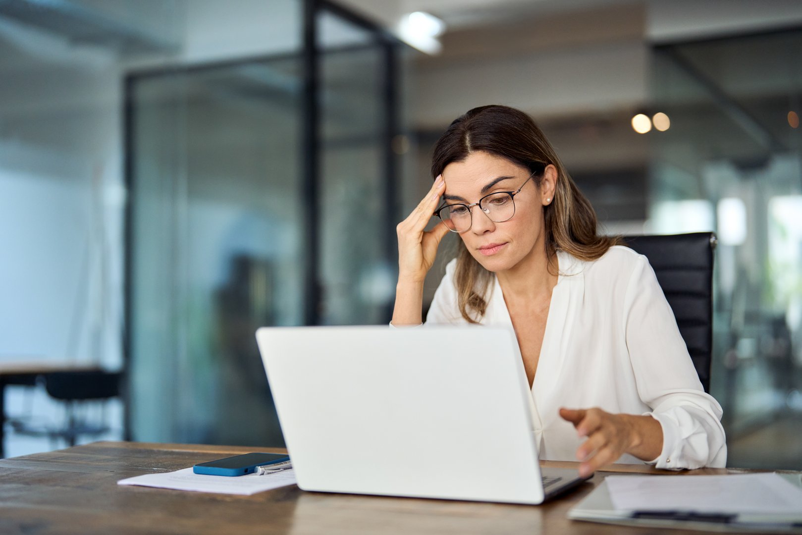 Worried fatigued mature business woman wearing glasses having headache at work showing emotional stress that leads to emotional eating patterns