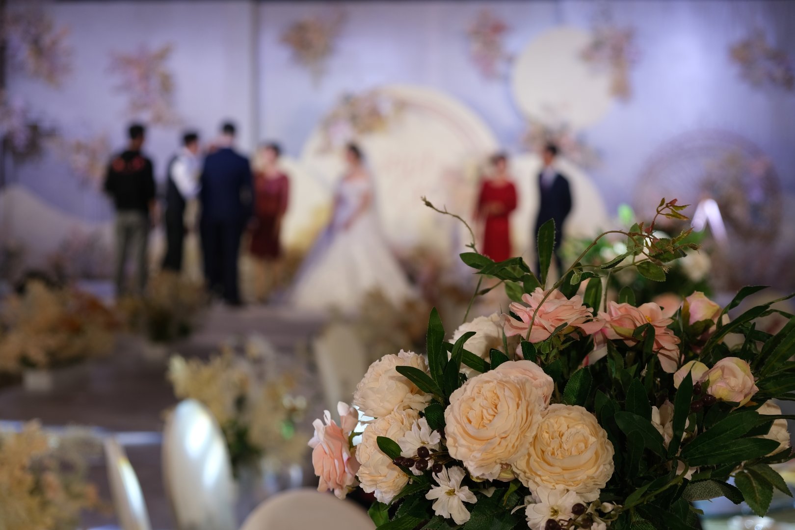 close up bouquet on wedding site. Blur bridegroom and bride on wedding stage. Chinese wedding ceremony