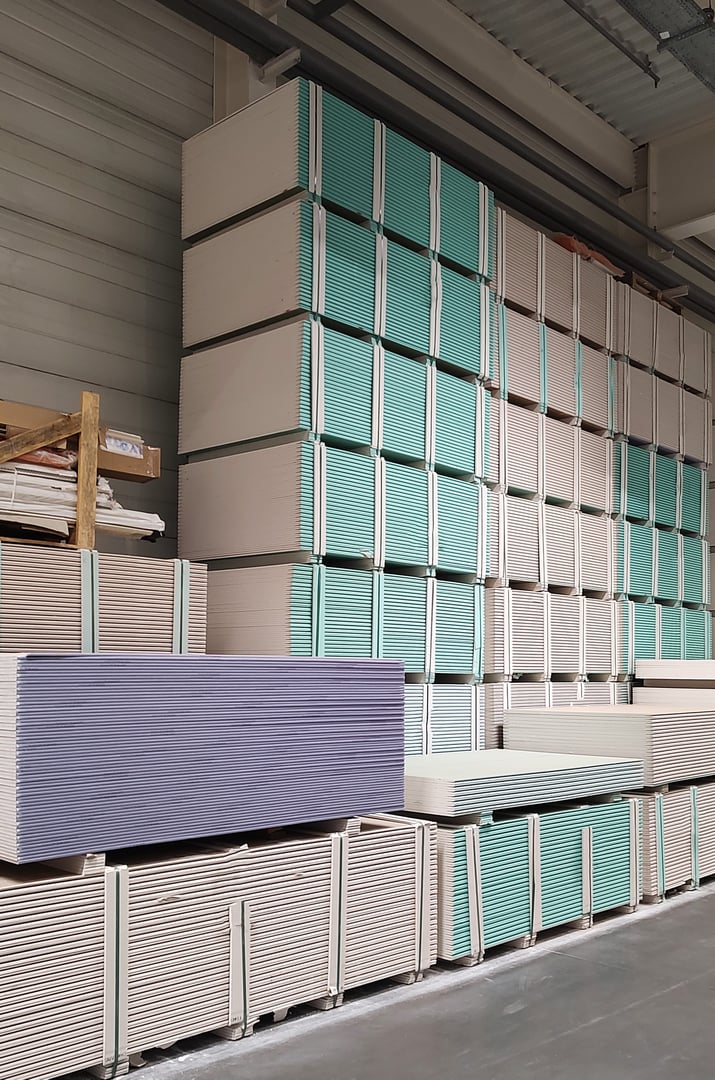 Warehouse with drywall gypsum plasterboard sheets stacked on pallets.