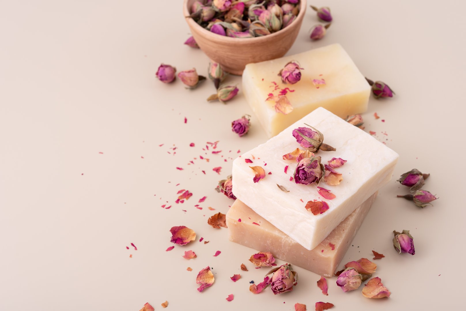 Handmade natural soap bars with dried rose petals on a beige background. Perfect for wellness, spa, organic skincare, aromatherapy, and romantic beauty concepts.