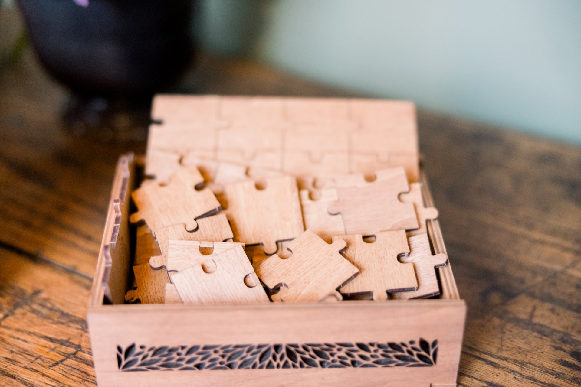 A wood box with wooden puzzle pieces on a table.