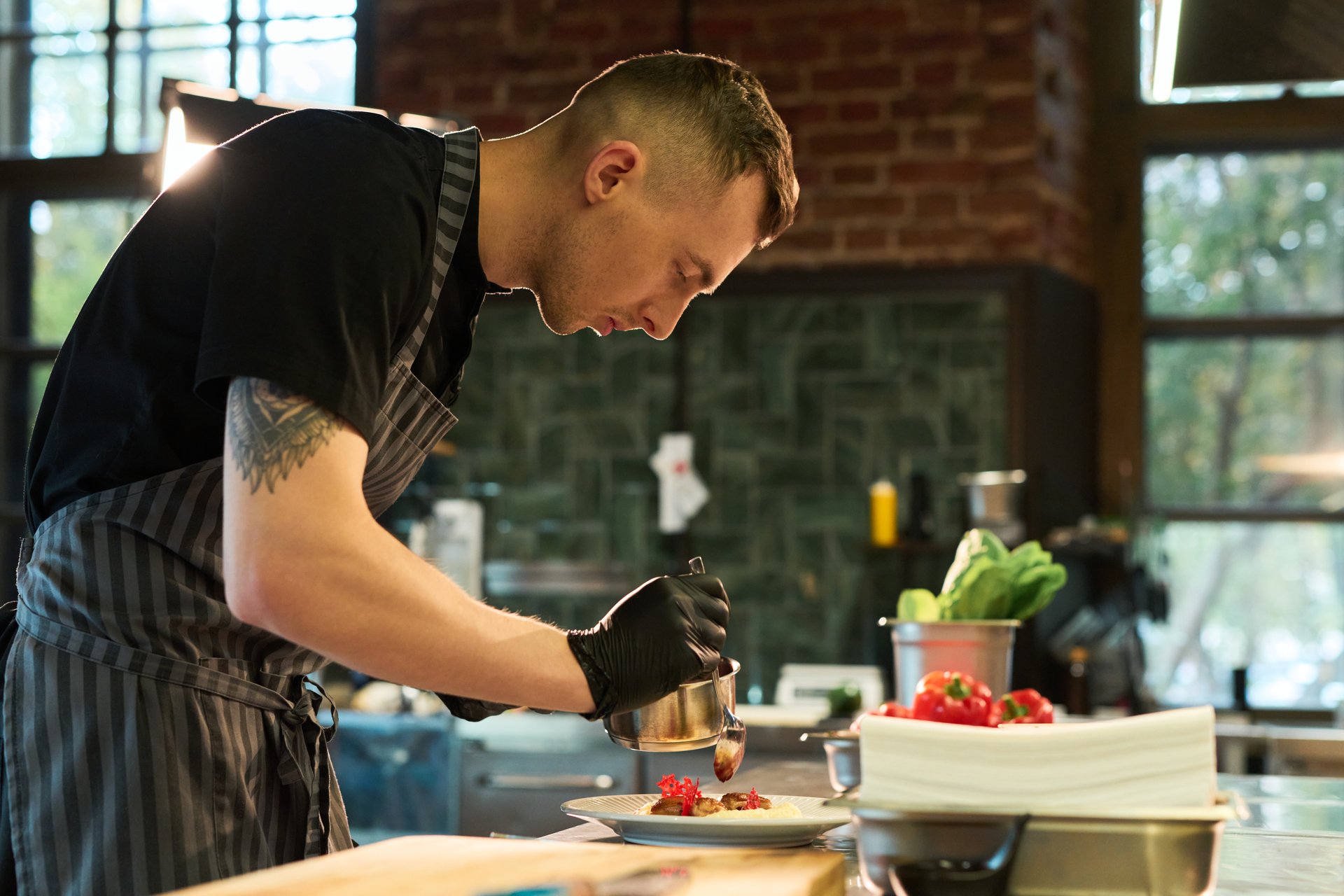 Chef profesional manipulando alimentos con guantes de nitrilo negros aptos para contacto con alimentos en cocina profesional