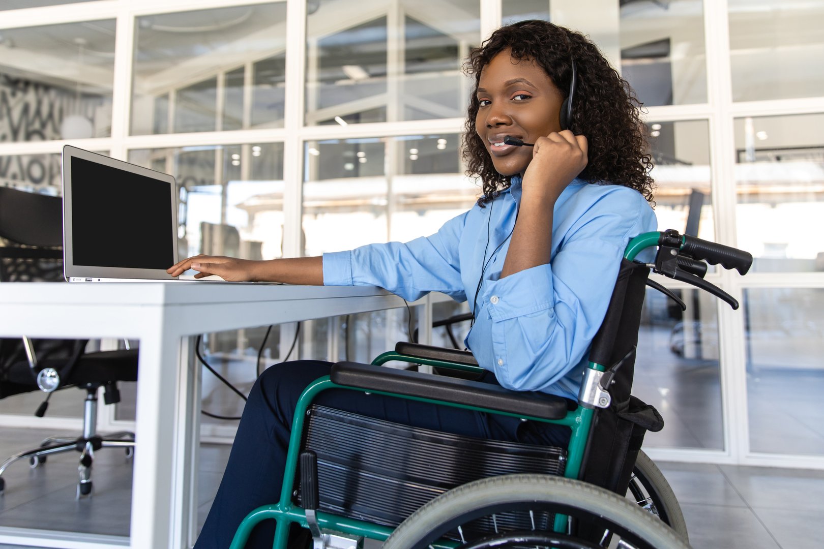 Disabled woman talking with clients over the phone from her office using headset to offer assistance in customer service